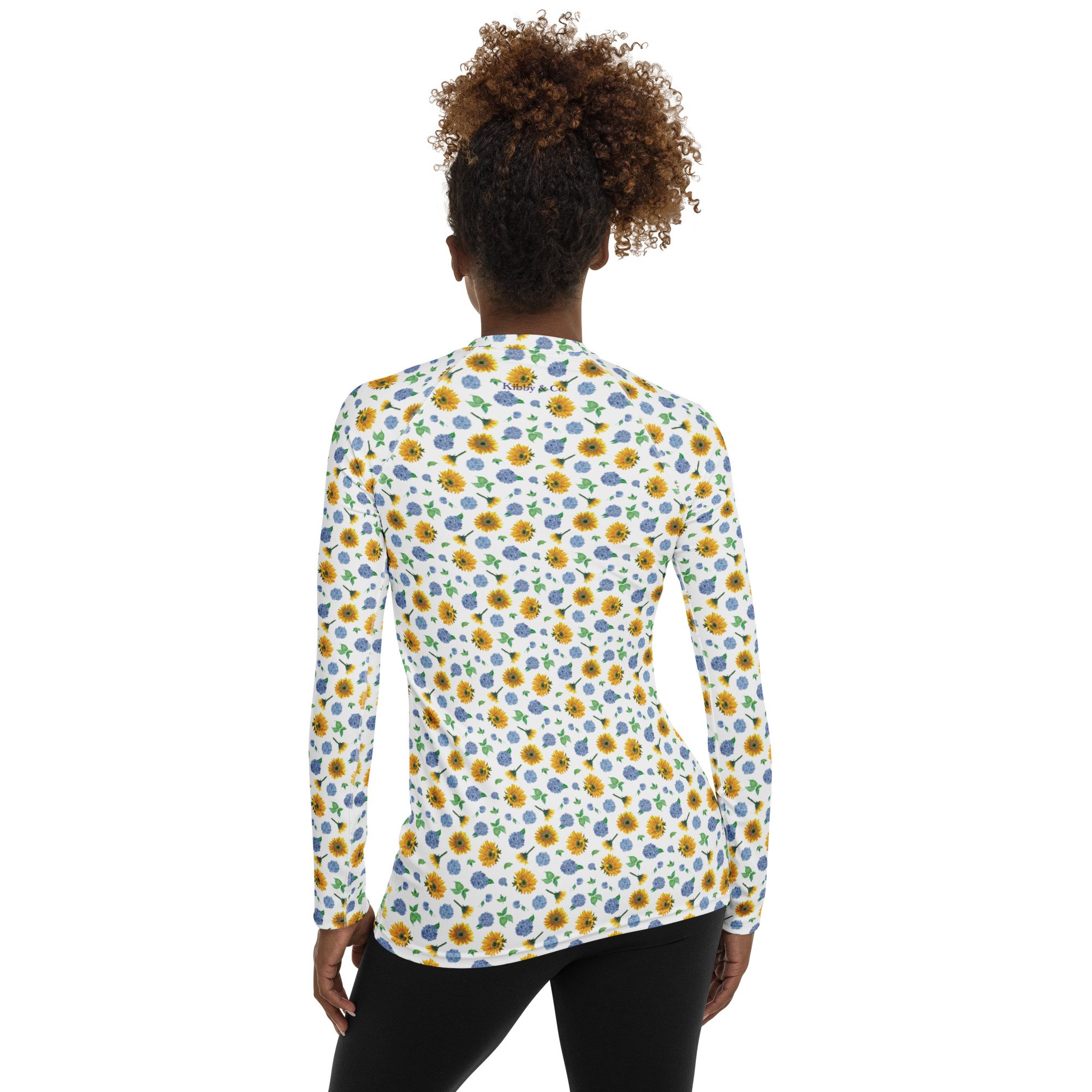 Rash guard back on model. Long sleeve, crew neck in Sunflower Hydrangea print, pretty, floral pattern by Kibby & Co. Blue, yellow, green, on white. Classic flower