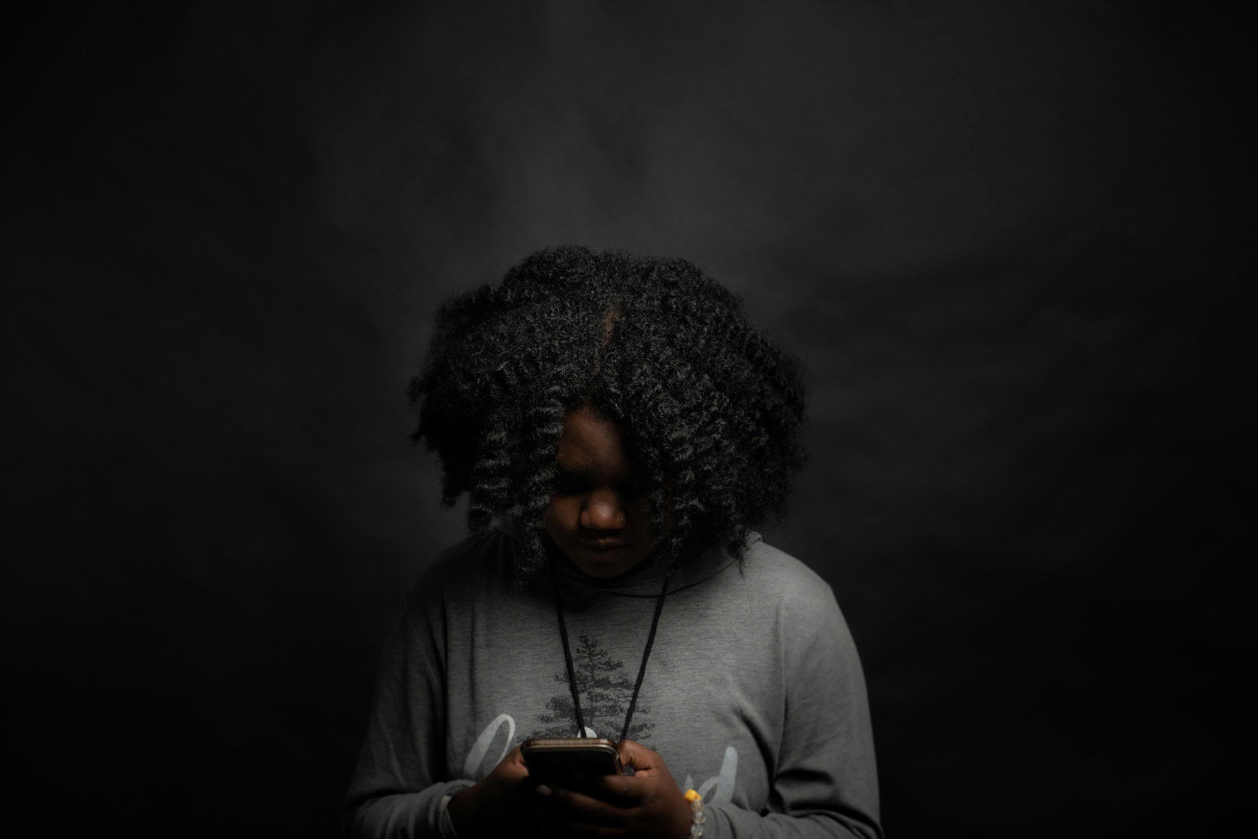 black woman looking down at her phone. black and white photo