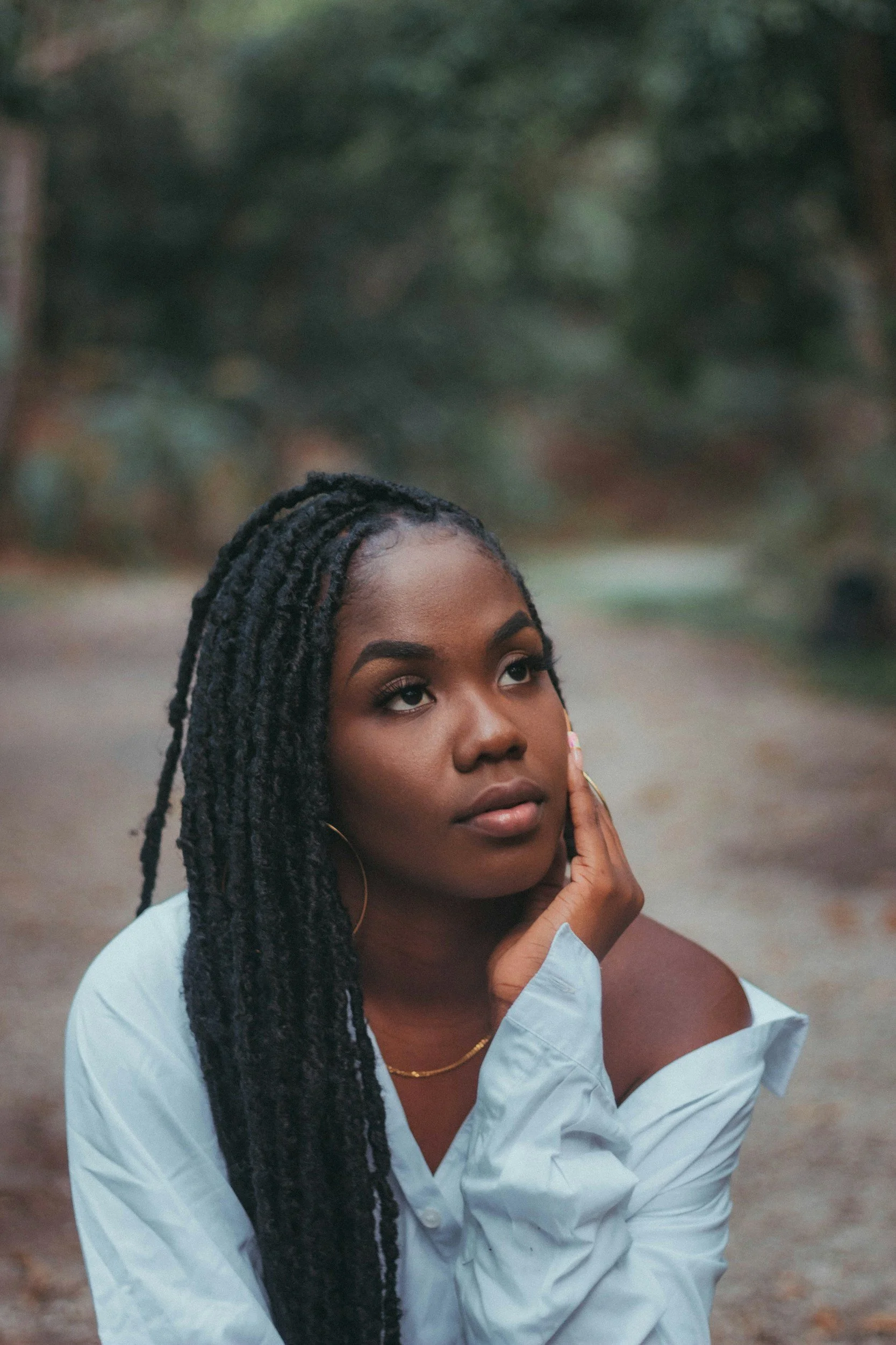 black woman with braids looking away with hand on her face