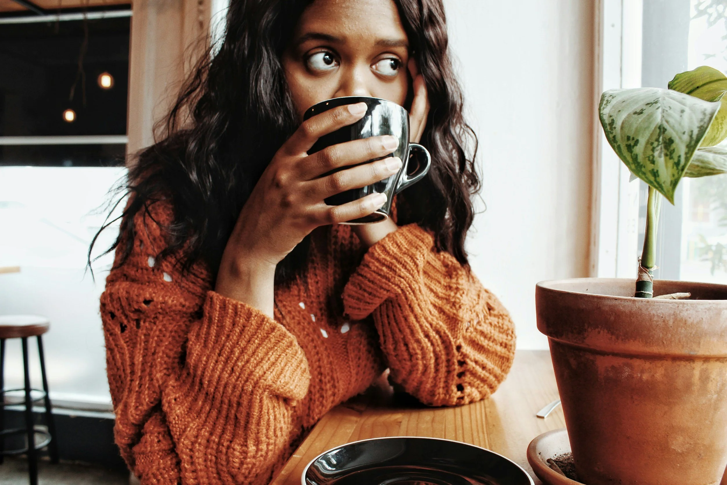 black woman sitting with cup looking away