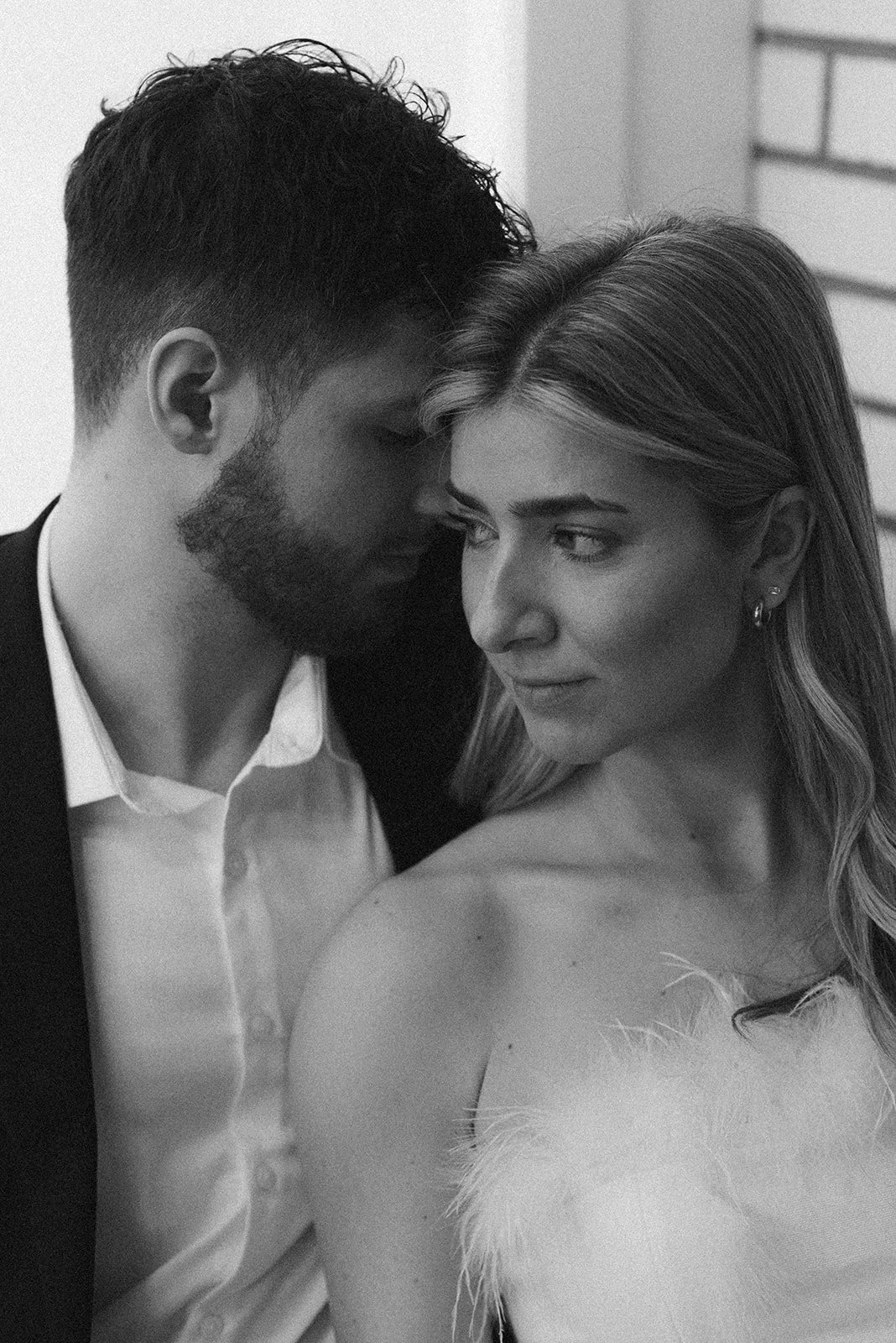 A black and white photo of a man and woman close together, with the man's forehead touching the woman's head, both looking down.