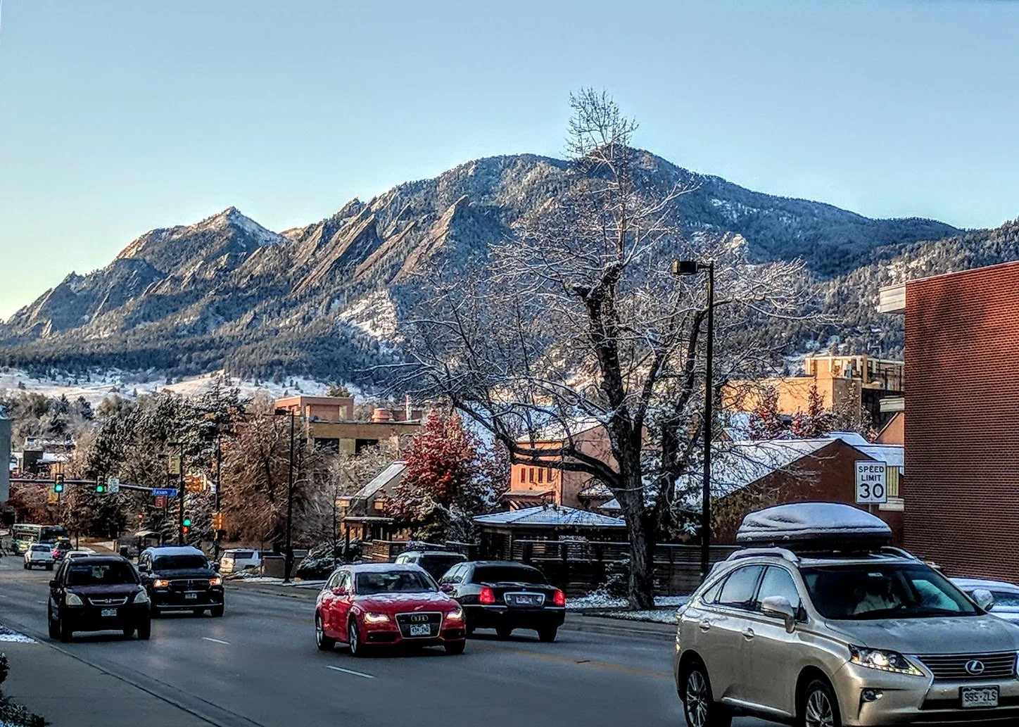 Many cars traveling on Broadway in front of snowy flatiron mountains