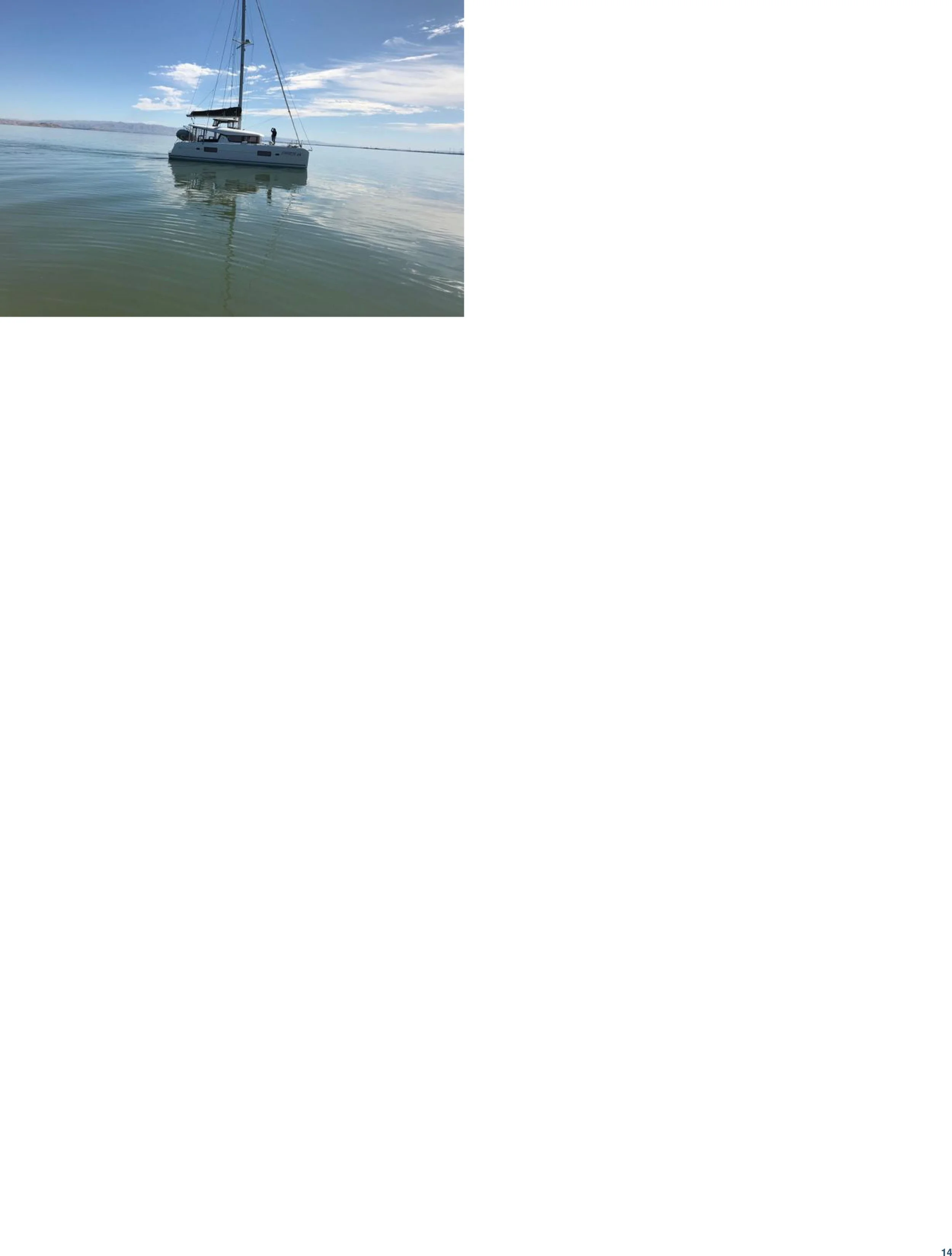 A sailboat floating on calm water with a cloudy sky above.
