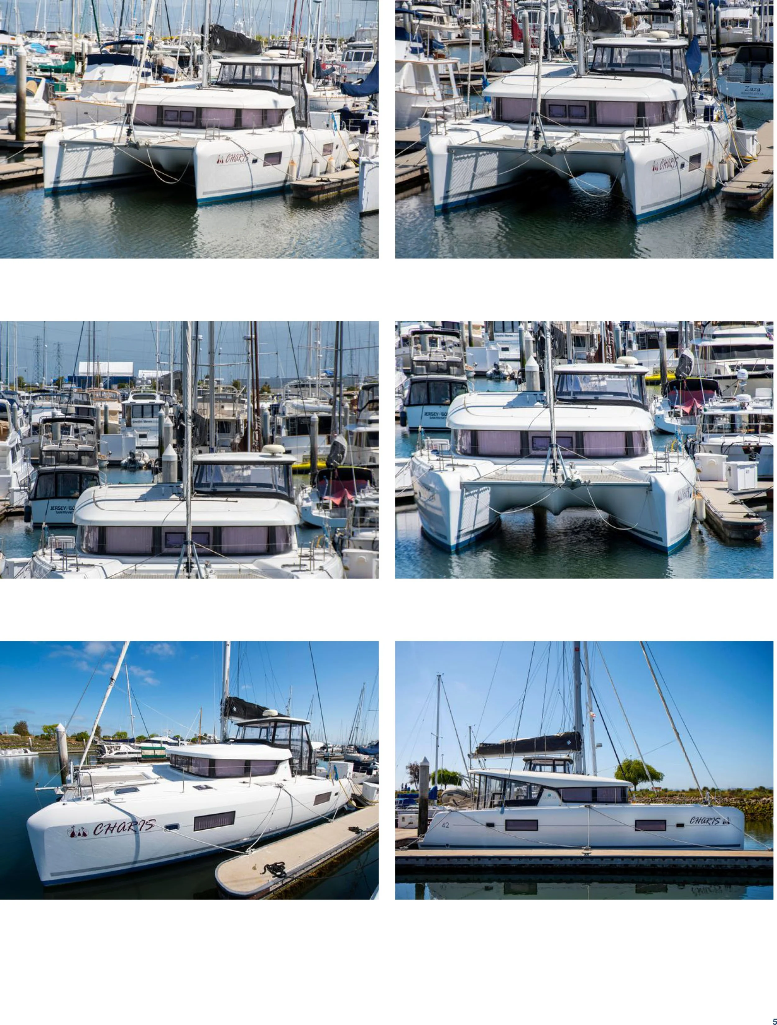 Multiple boats docked at a marina, including sailboats and motor yachts, with clear blue skies and calm water.
