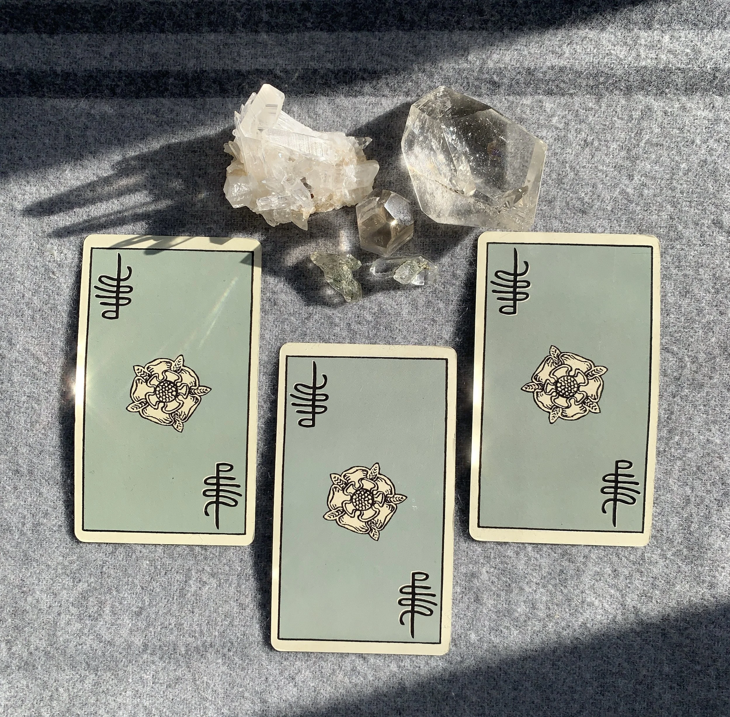 Three tarot cards and crystals used for intuitive tarot and astrology readings.
