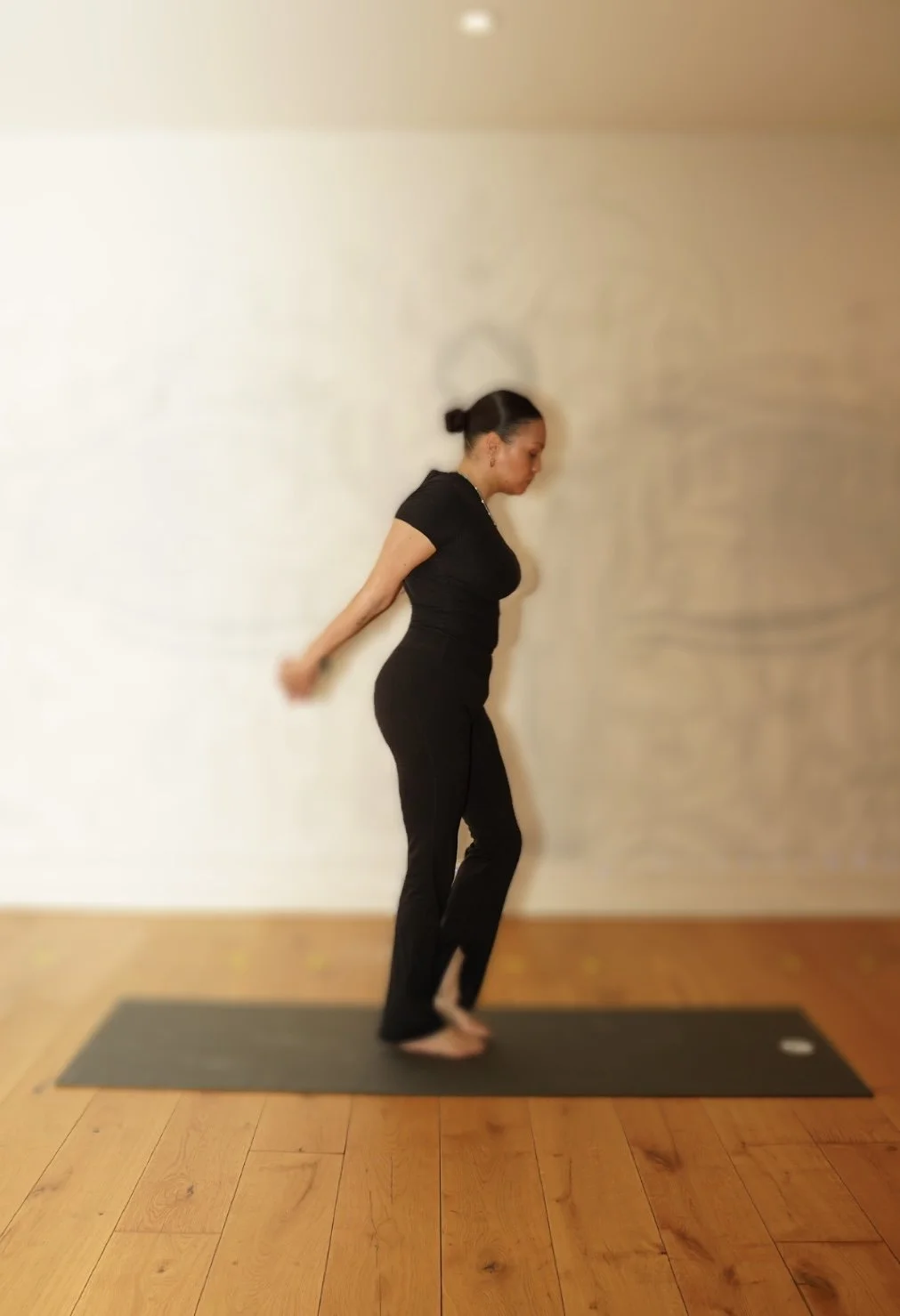 private yoga instructor guiding embodied yoga practice indoors, wearing black athletic wear
