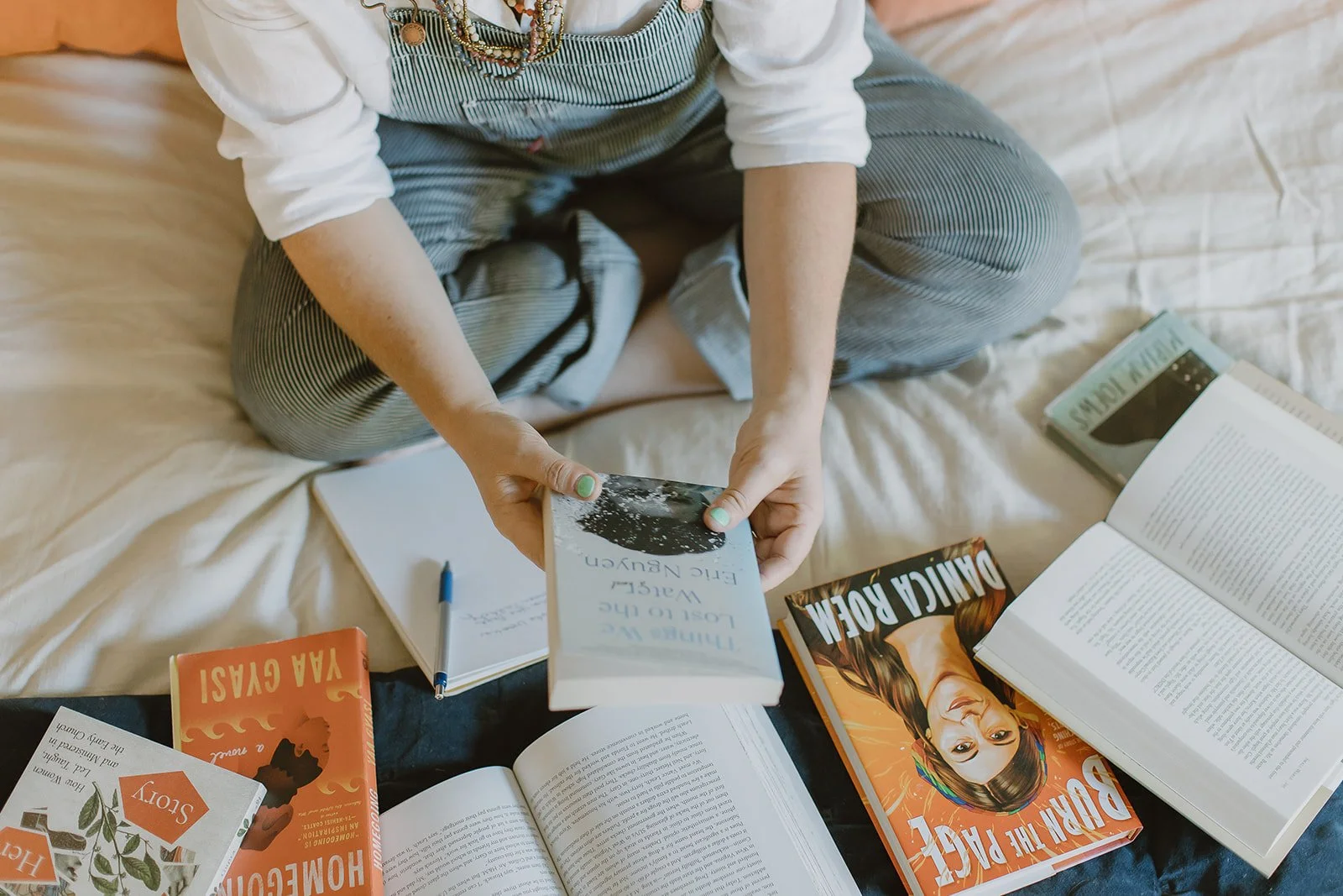 a woman looking over a stack of books