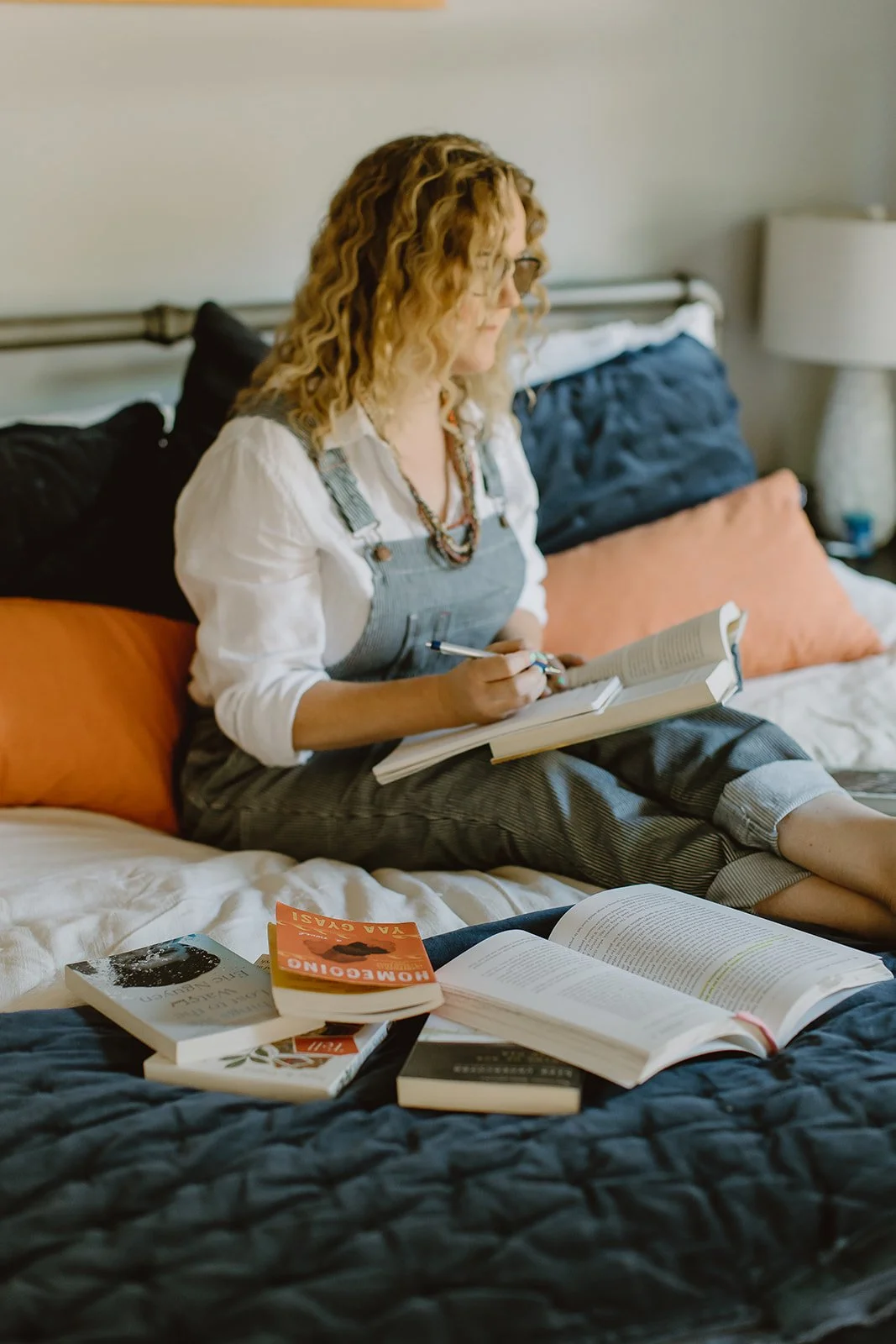 a woman sits on a bed taking notes from a book