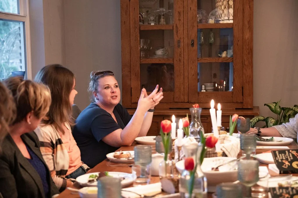women sit around the table discussing a book