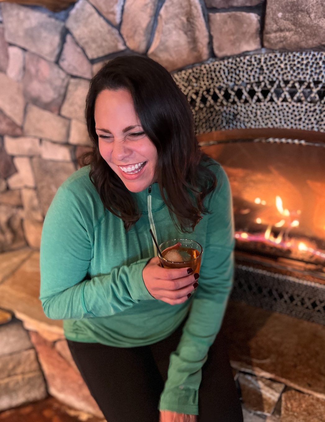 Woman Laughing at Fireplace with an Old Fashioned Drink