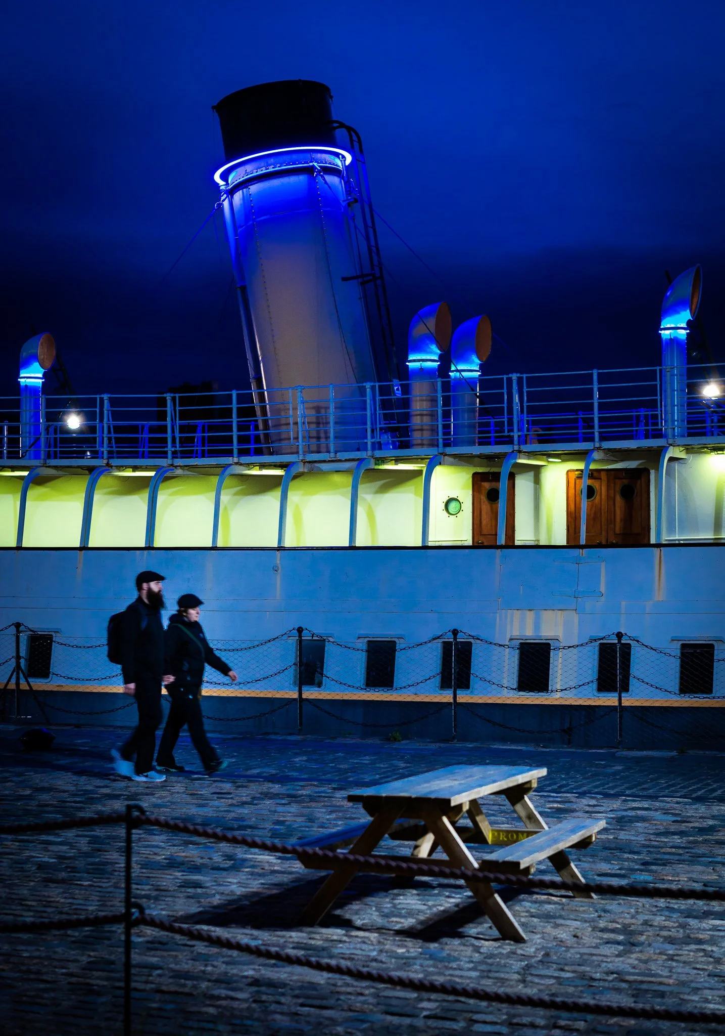 Couple strolling at night passing the SS Nomadic, Belfast