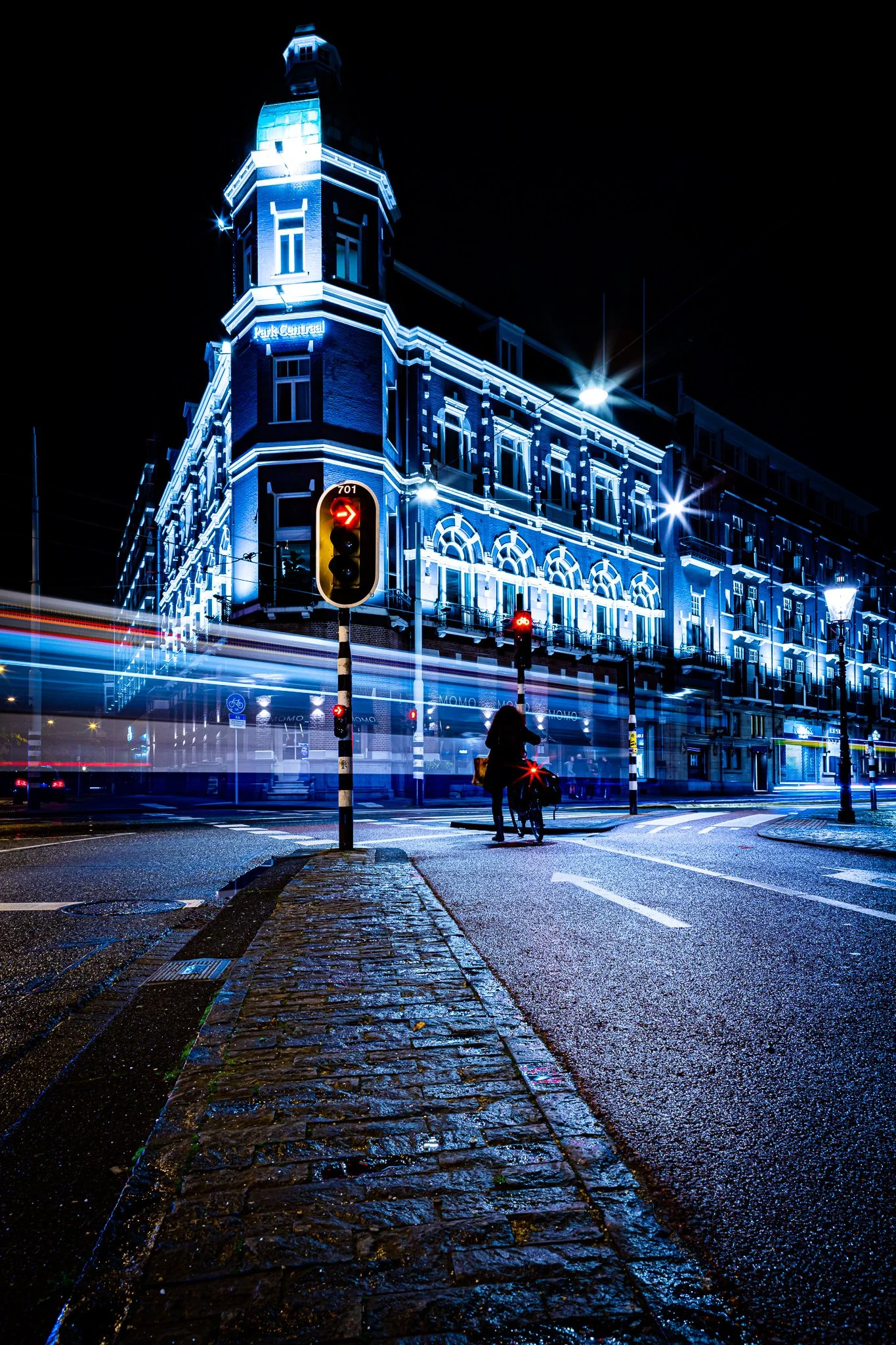 Park Hotel, Amsterdam with cyclist and tram light trail at night