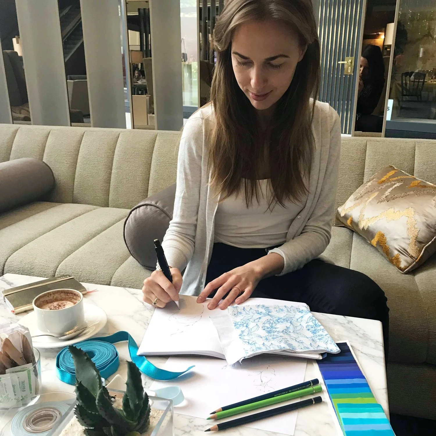 Woman sitting on a sofa writing in a notebook