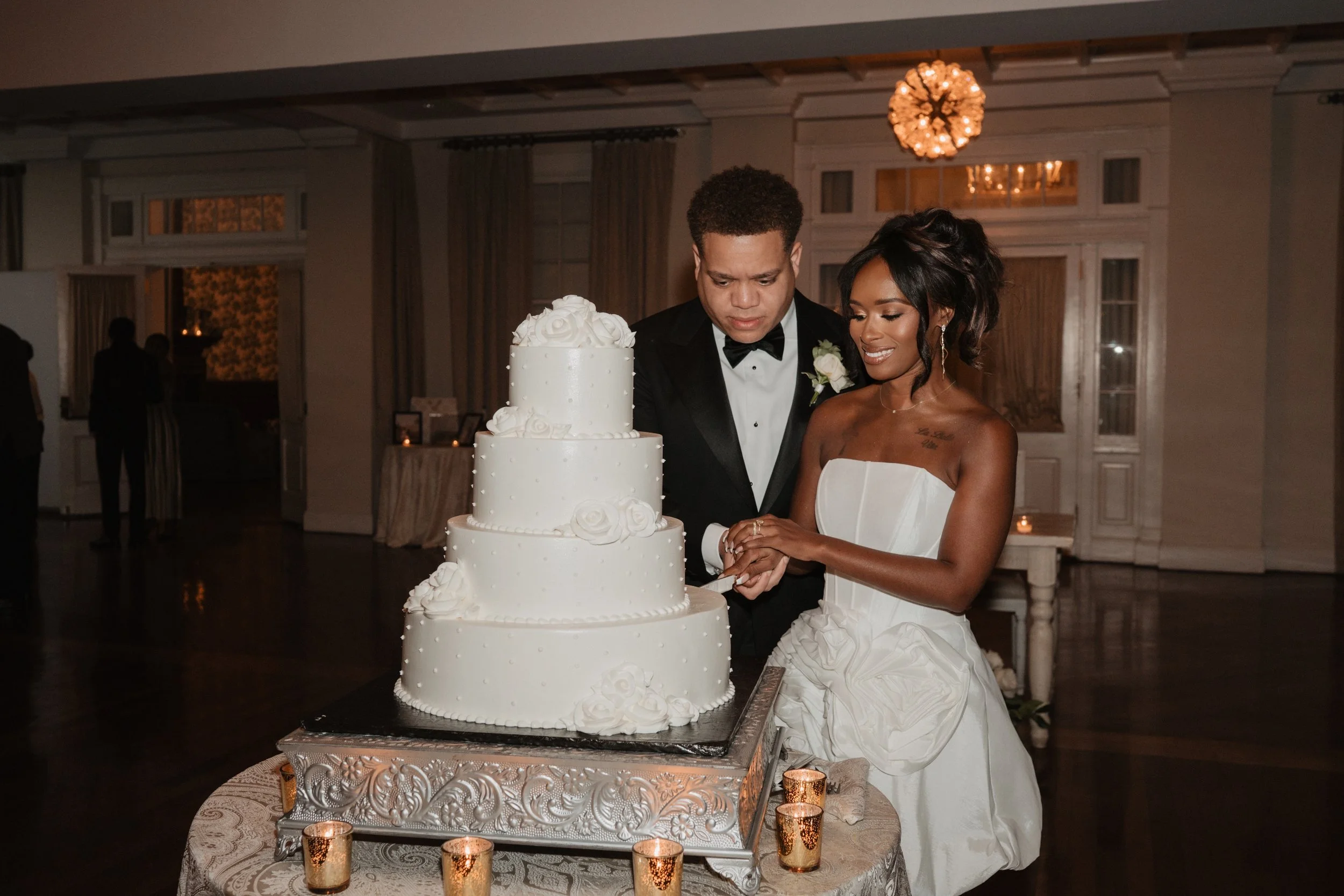 Bride and groom cutting wedding cake in a decorated banquet hall.