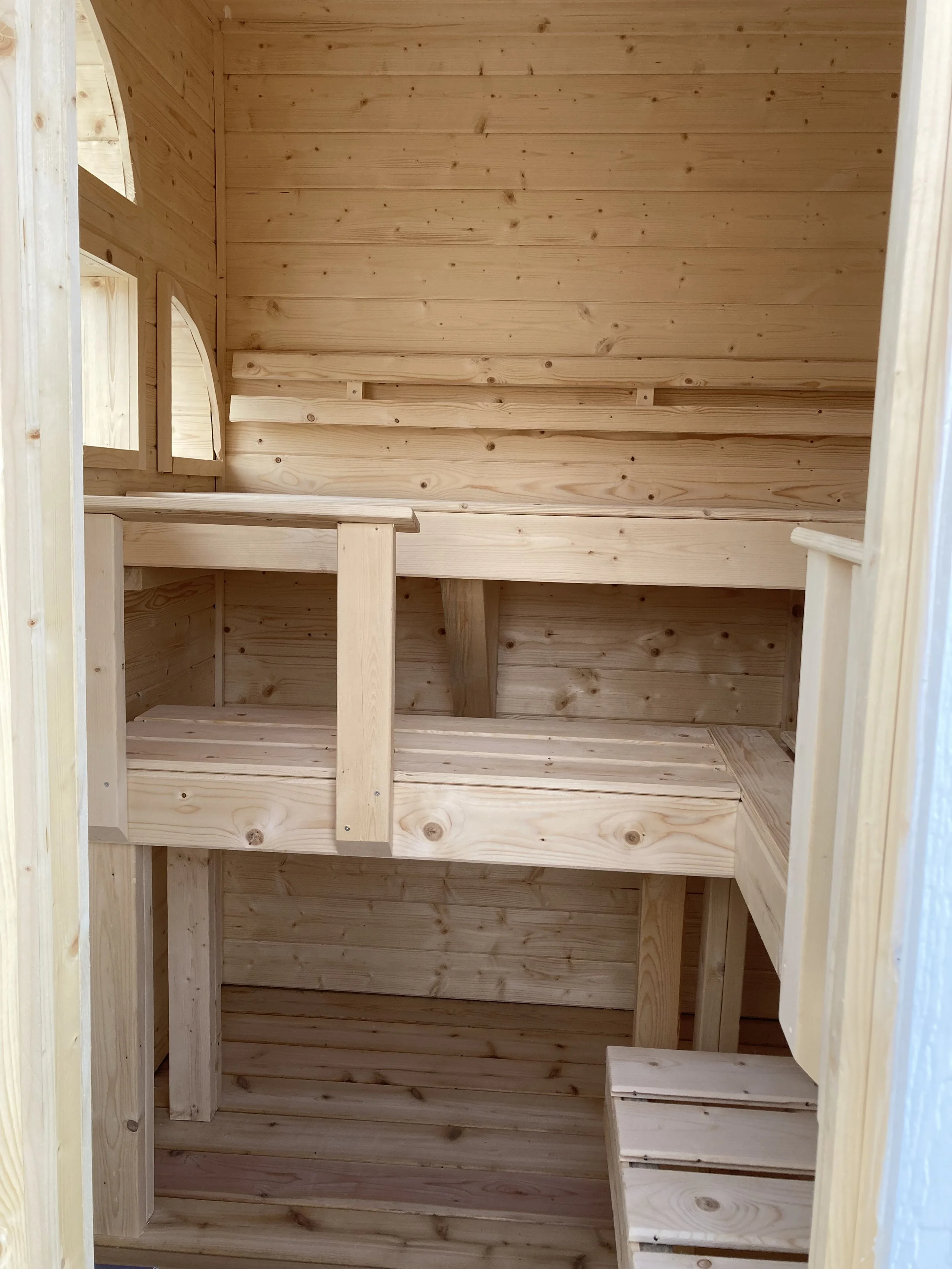 Spruce sauna interior with three levels of seating, ergonomic back rests, and foot rests