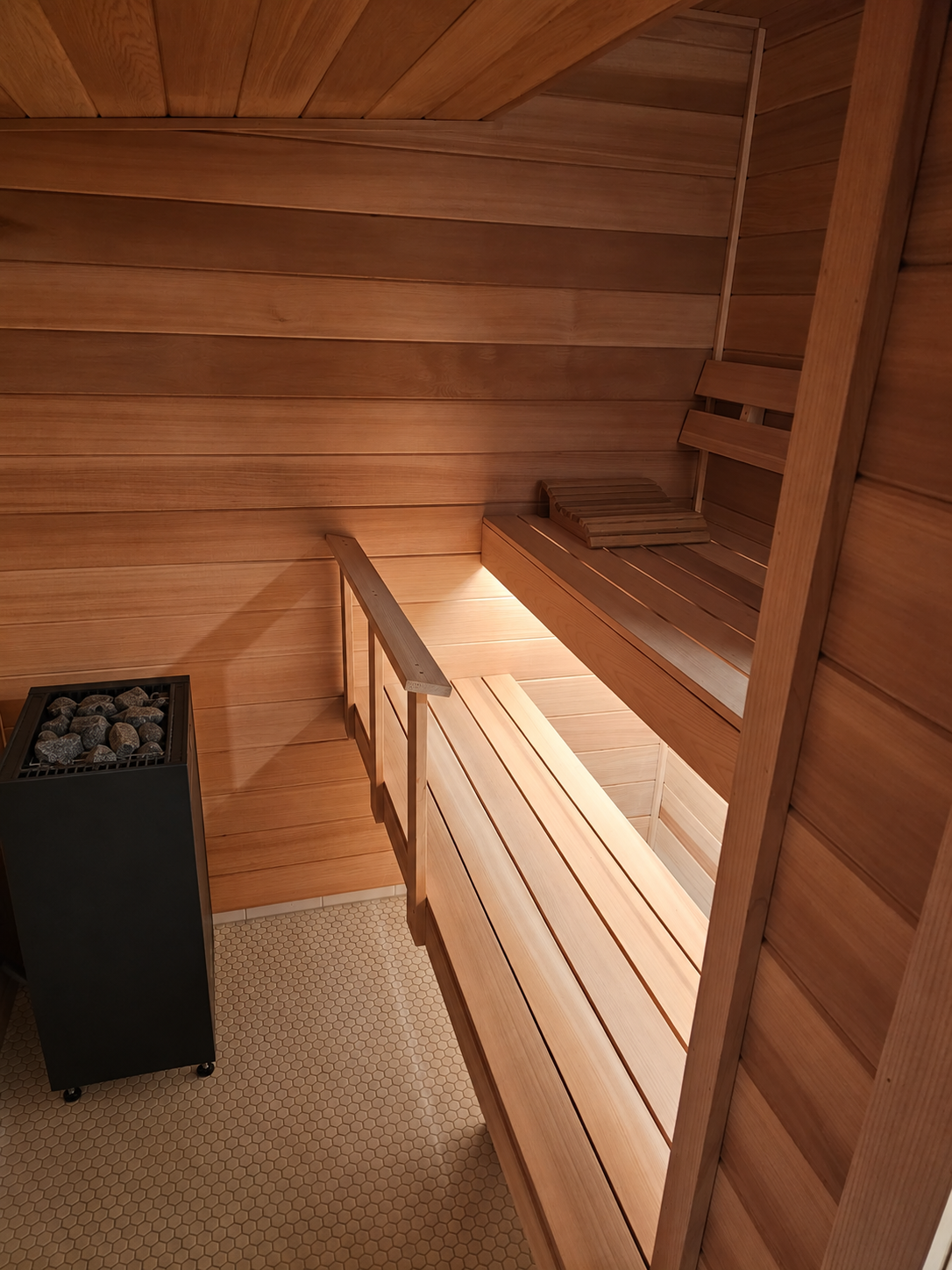 Basement sauna with Harvia Spirit heater, clear cedar interior, and tile floor. LED lighting