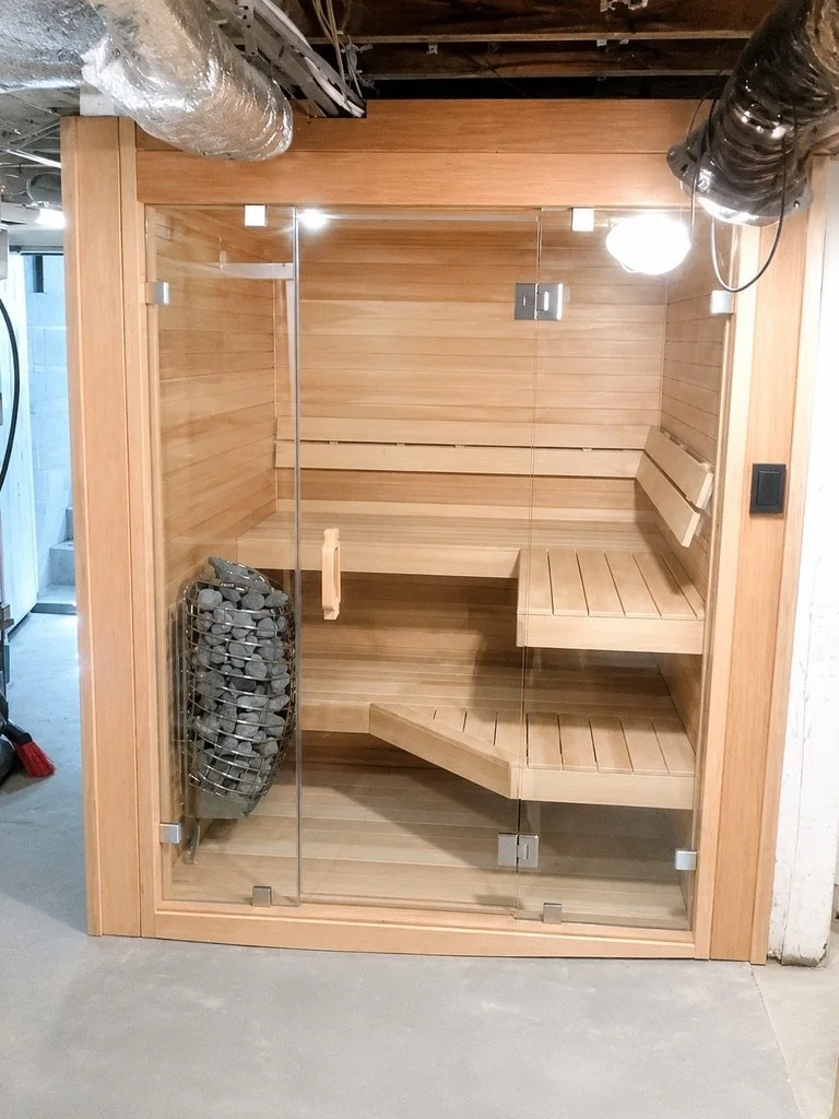 Basement sauna with clear cedar interior, glass front, and Harvia Spirit heater
