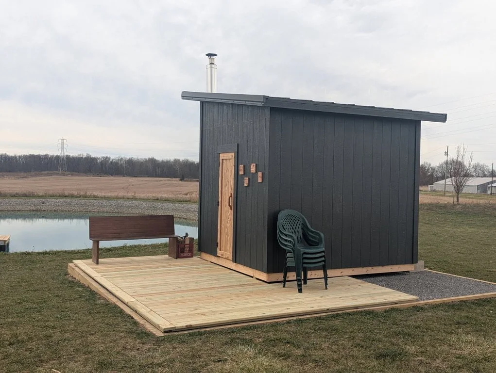 Large modern outdoor sauna beside a pond