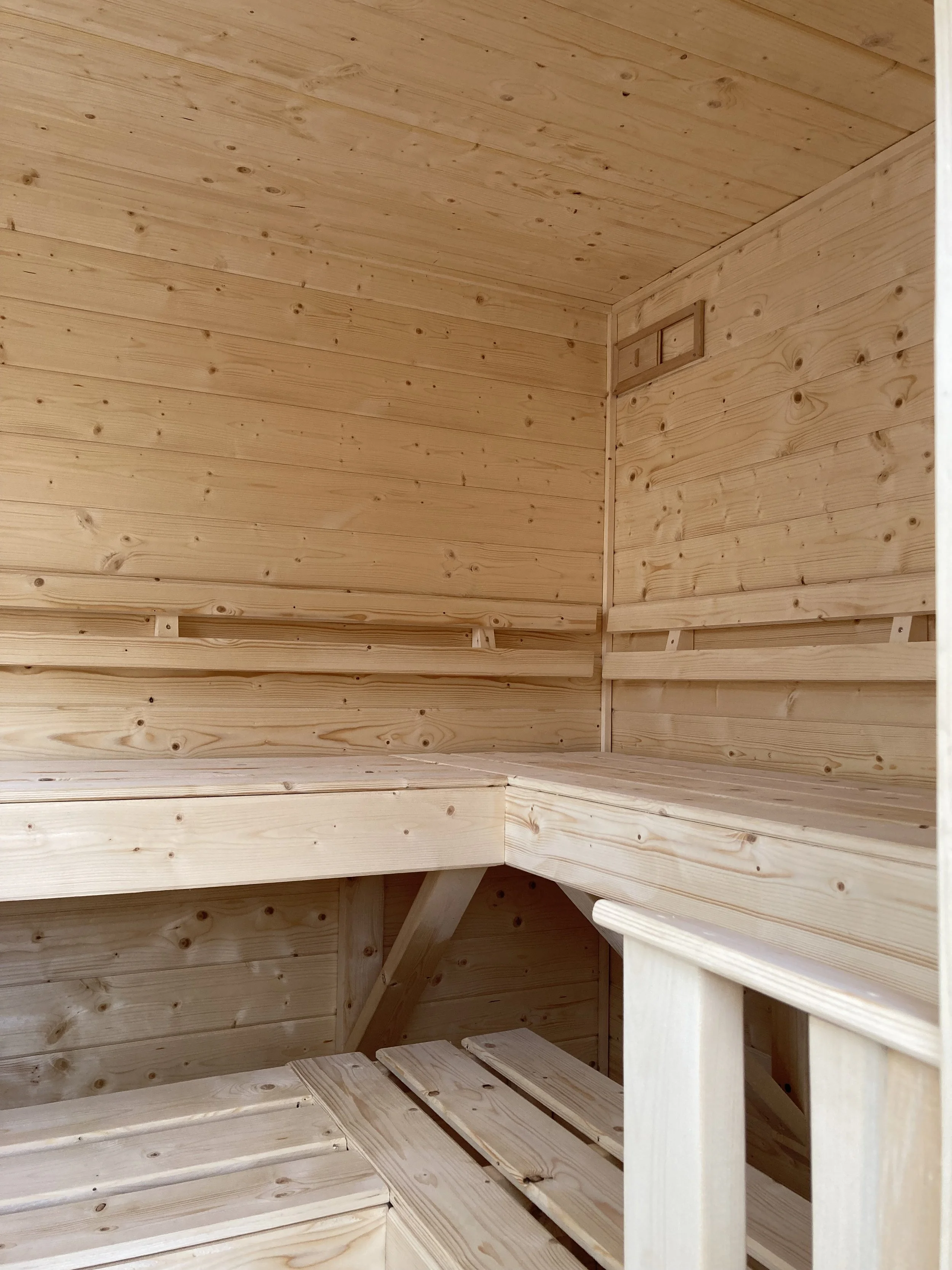 Spruce sauna interior with ergonomic back rests, foot rests, and upper vent