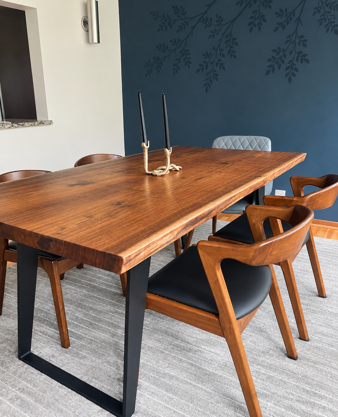 Live edge walnut slab table with tapered metal legs and matching walnut chairs with leather upholstery