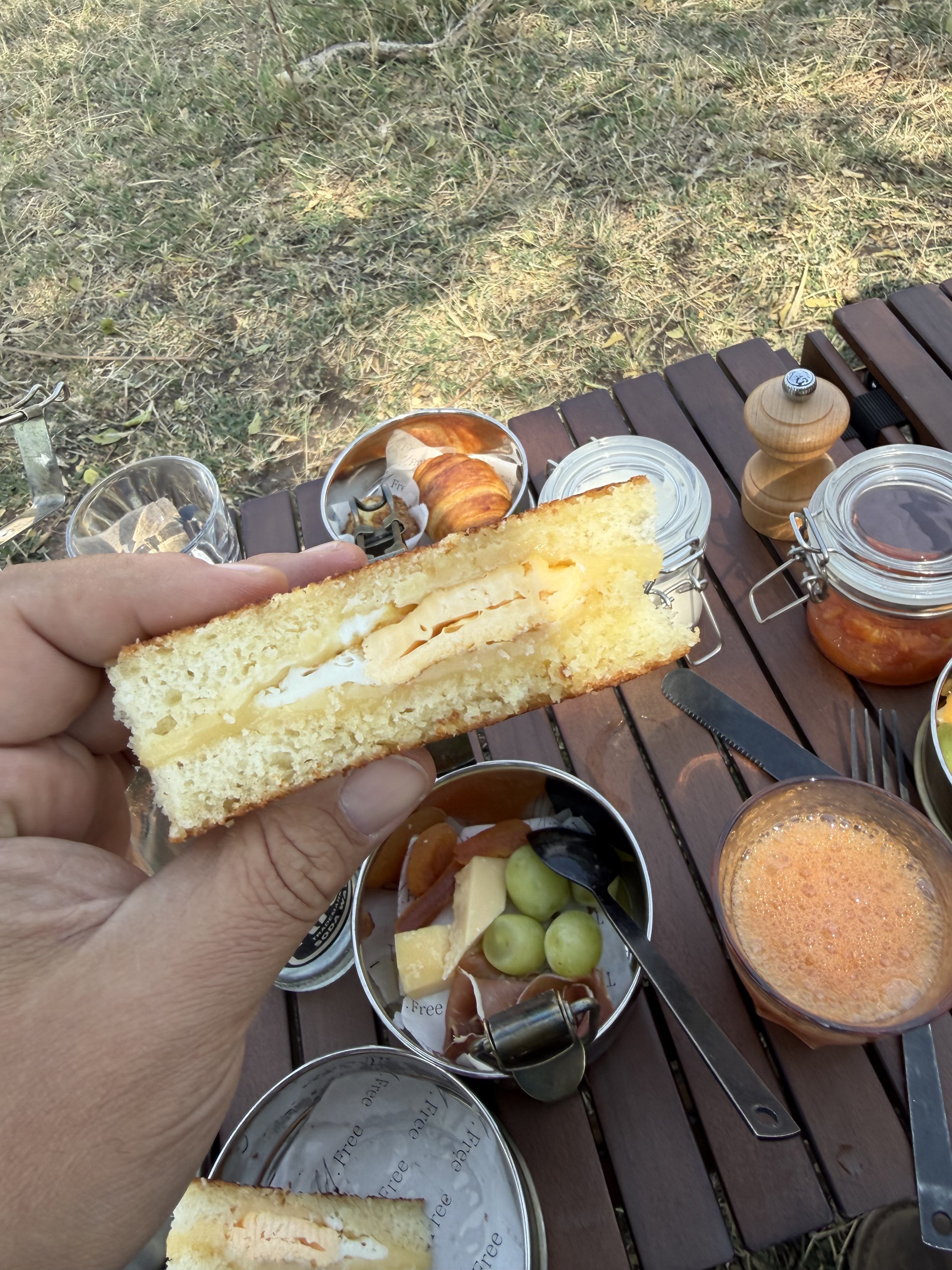 Egg and cheese sandwich at Mila's bush breakfast, with grapes, cheese and juice on the table