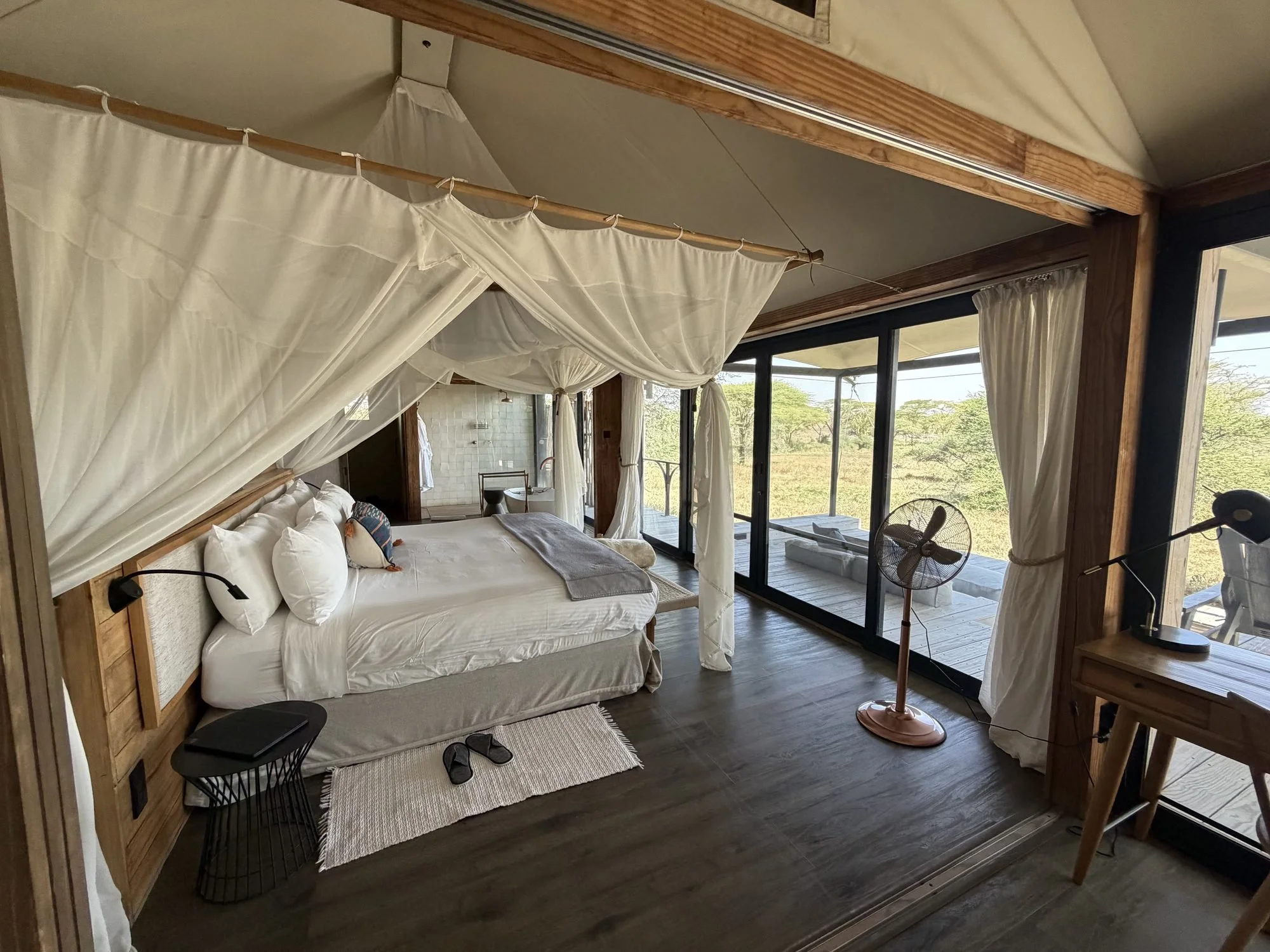 Canopy bed beside sliding glass doors in a Lemala Nanyukie suite
