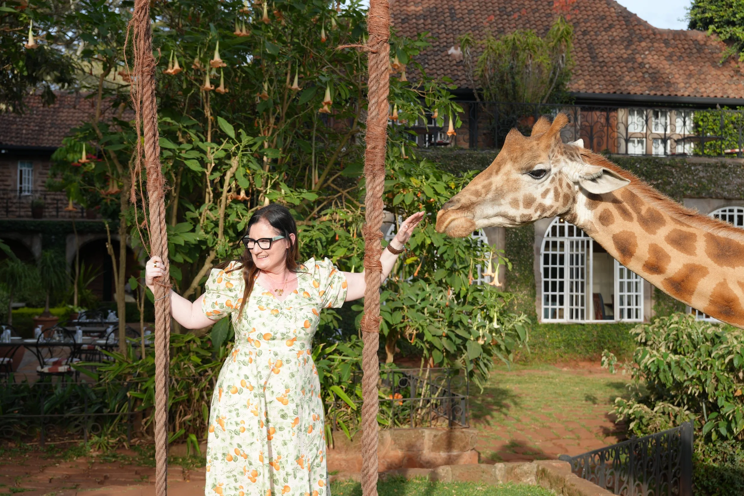 woman at giraffe manor swing with giraffe