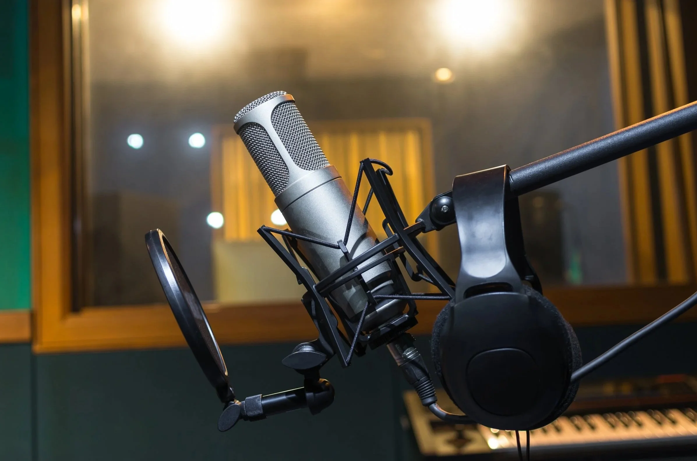 A professional studio microphone mounted on a stand with a pop filter, in a recording studio.
