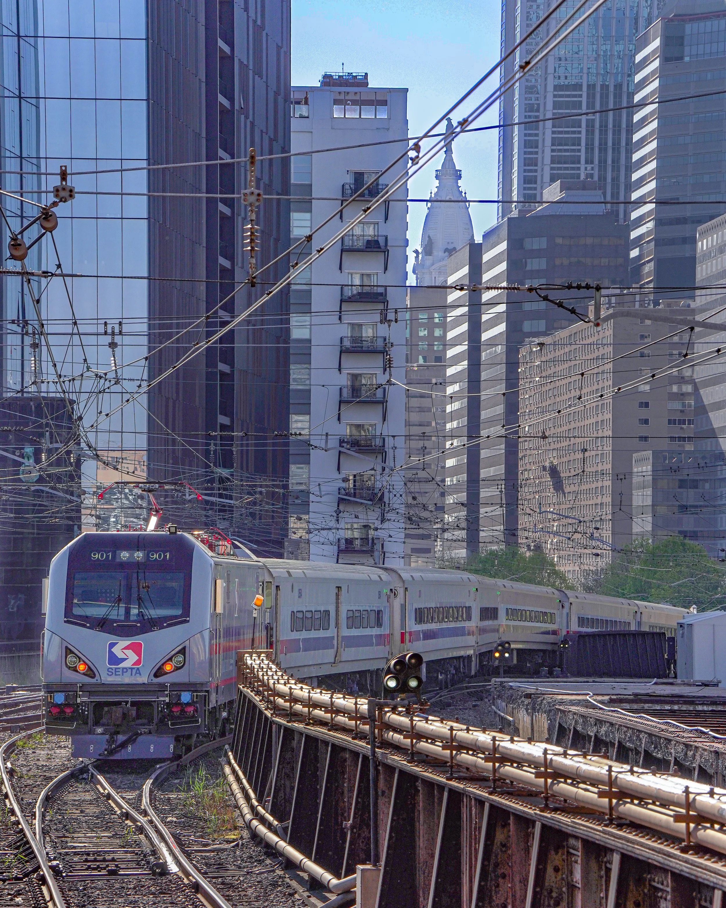 A train moving along tracks through a city with tall modern buildings in the background.
