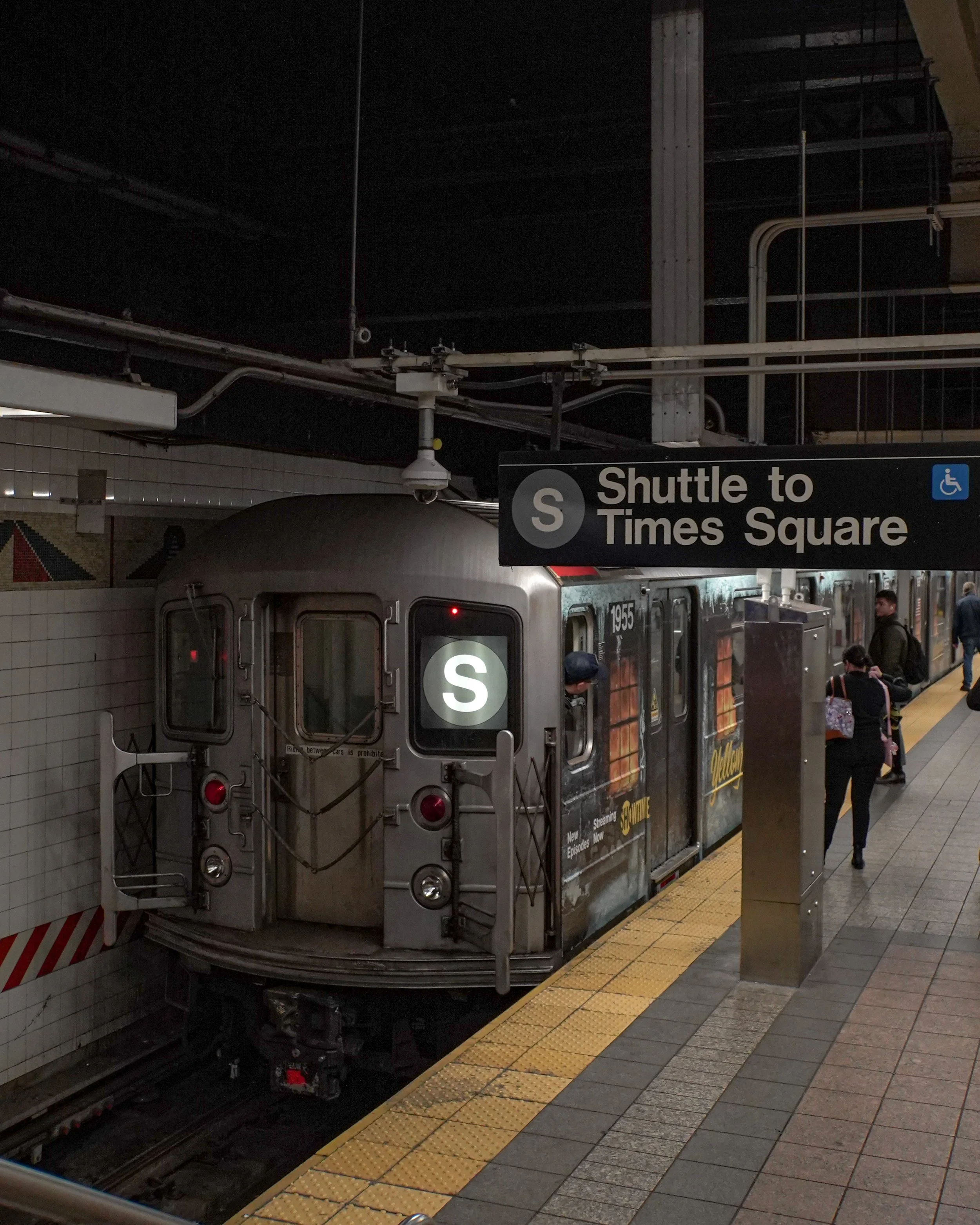 Subway train at Grand Central Station with a sign indicating shuttle to Times Square and an accessible icon.