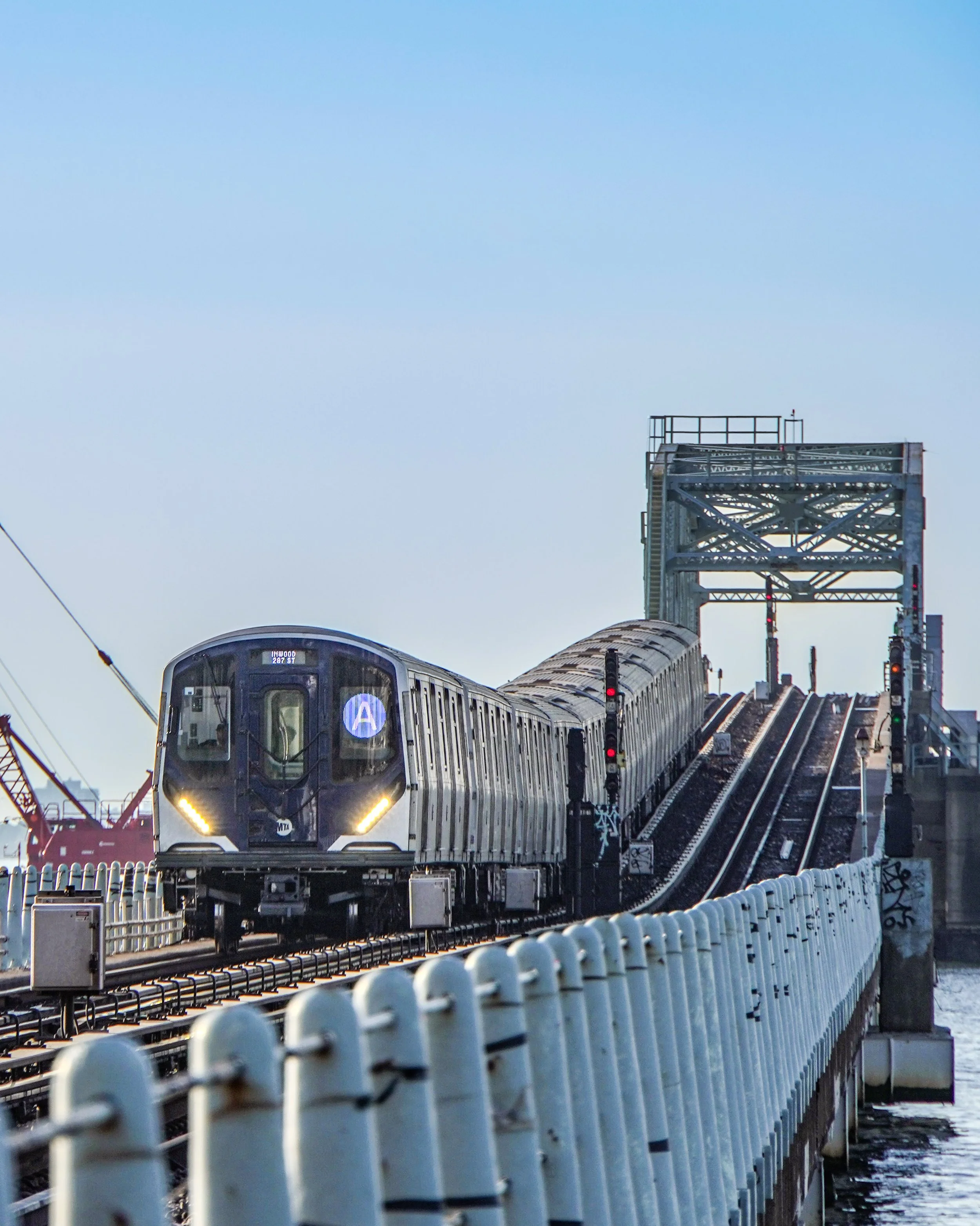 A modern subway train traveling on an elevated track with a blue sky in the background.