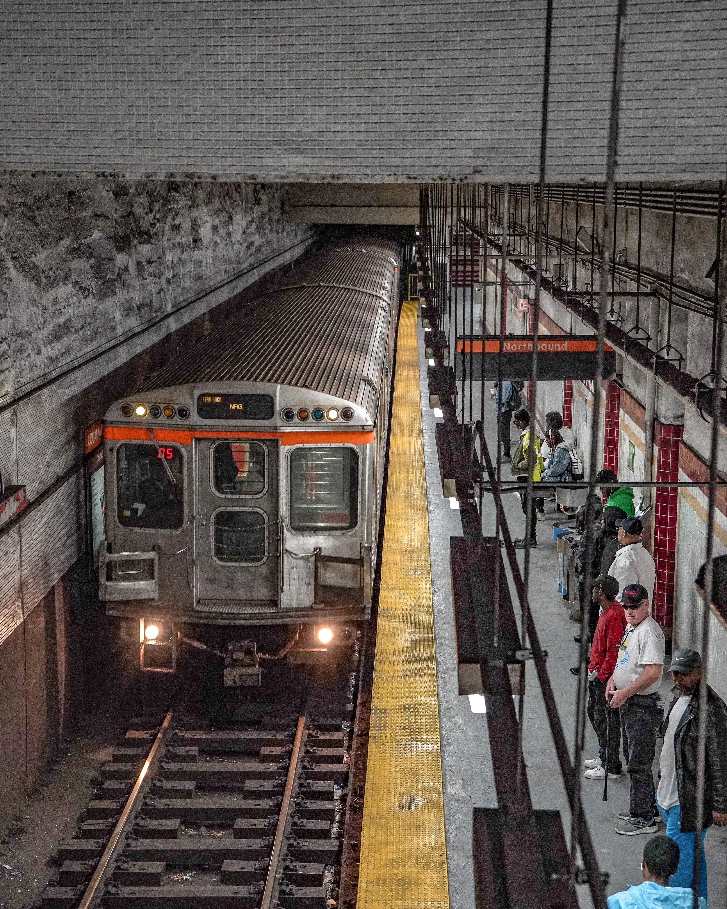 A Septa subway train arriving at an underground station with people waiting on the platform.