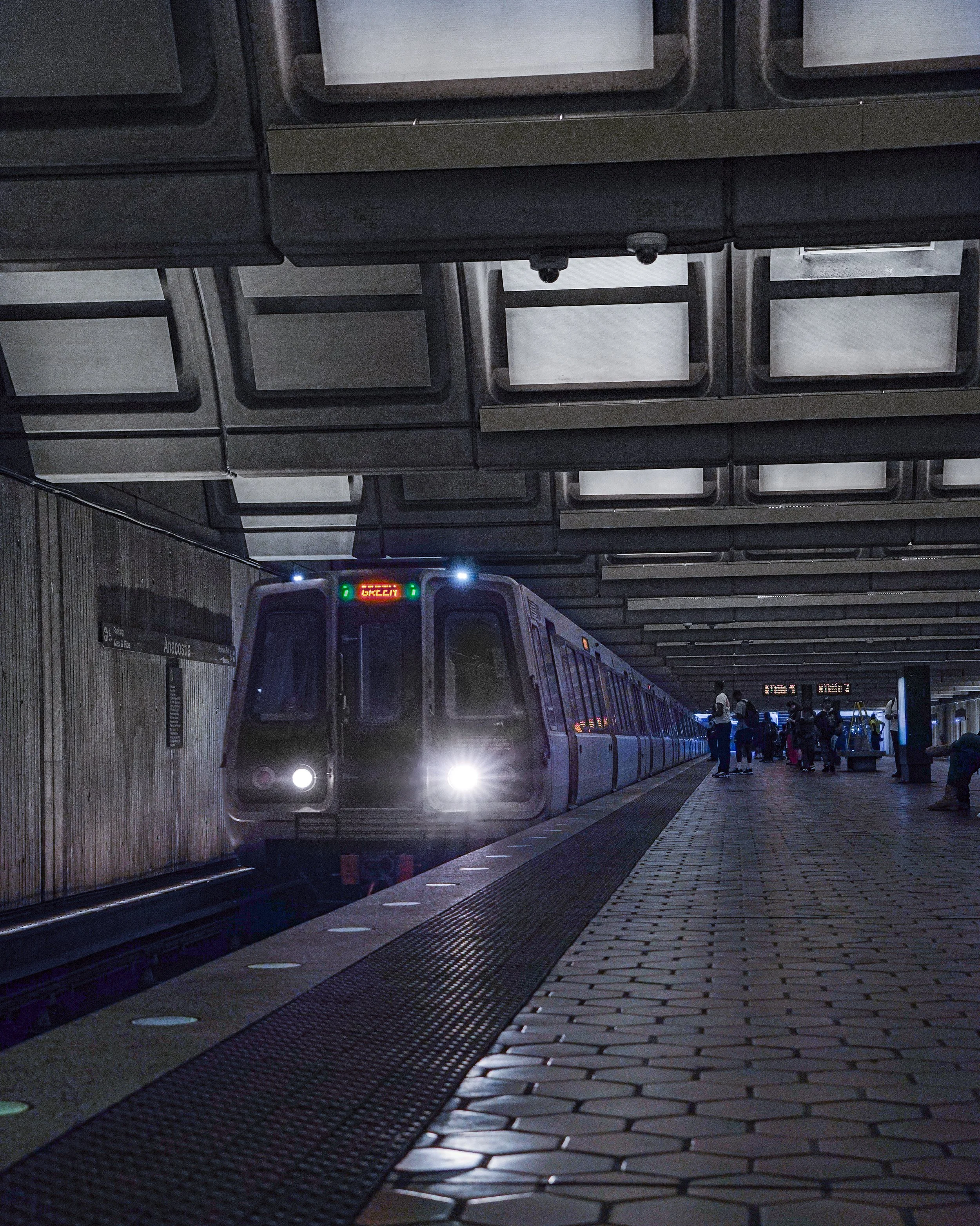 A modern subway train arriving at an underground metro station with passengers waiting on the platform.