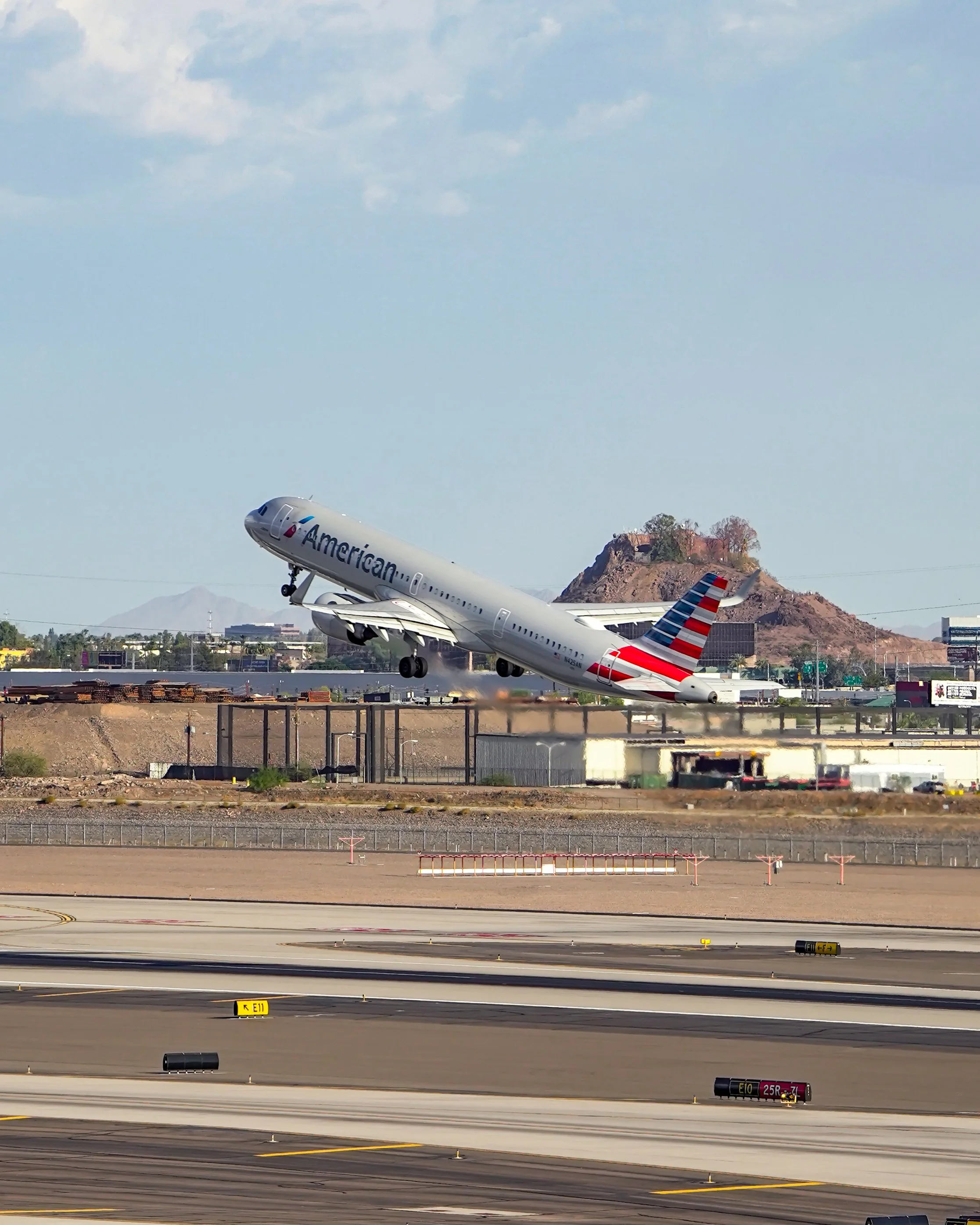 An American Airlines airplane during takeoff at an airport with mountains in the background.