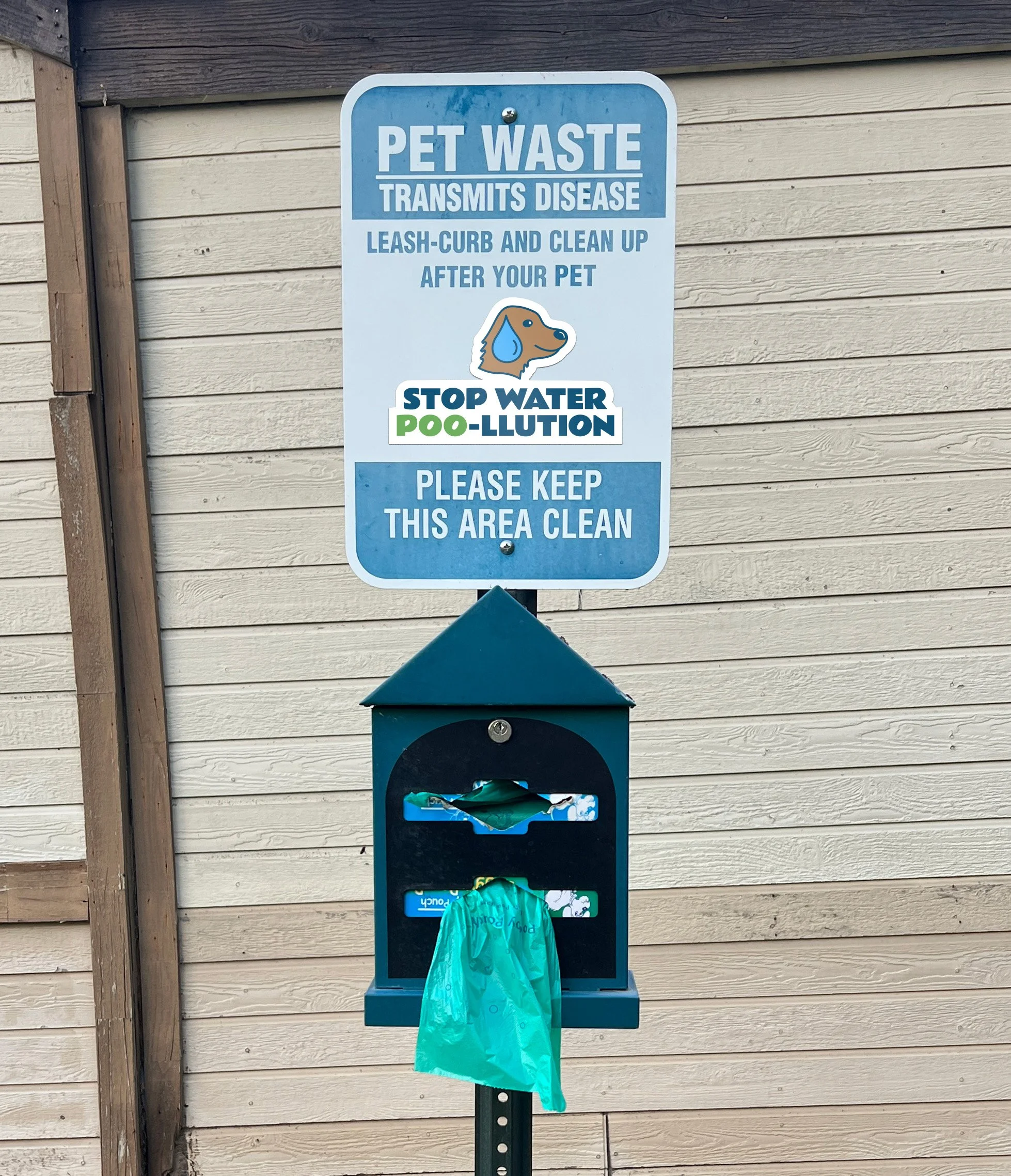 Pet waste sign with sticker on it that reads "STOP WATER POO-LLUTION"