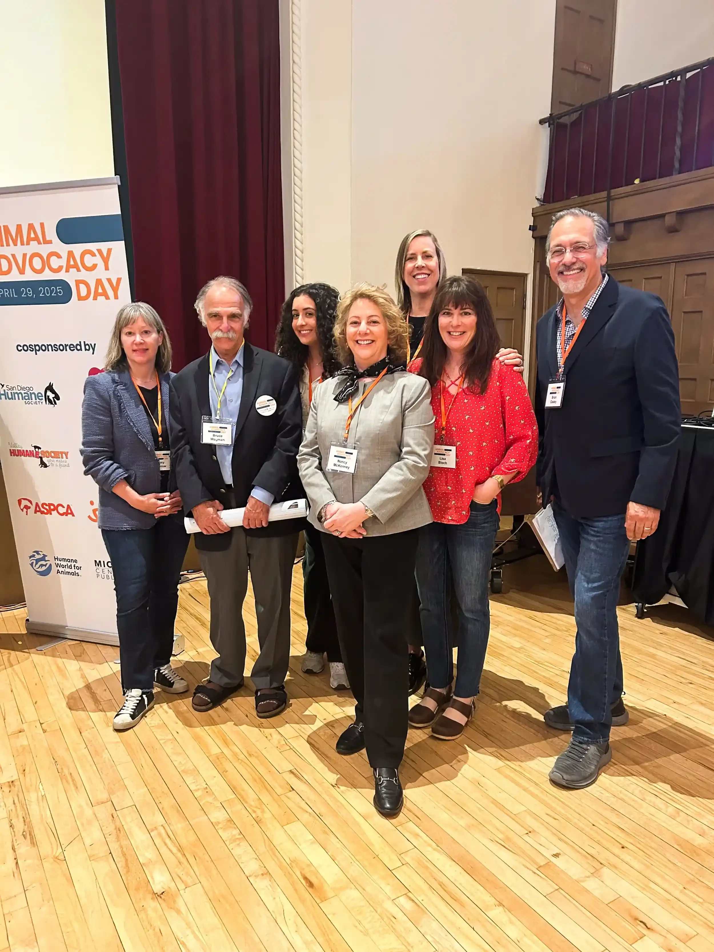 A group of people pose for a photo, they wear lanyard that say "Animal Advocacy Day 2025".