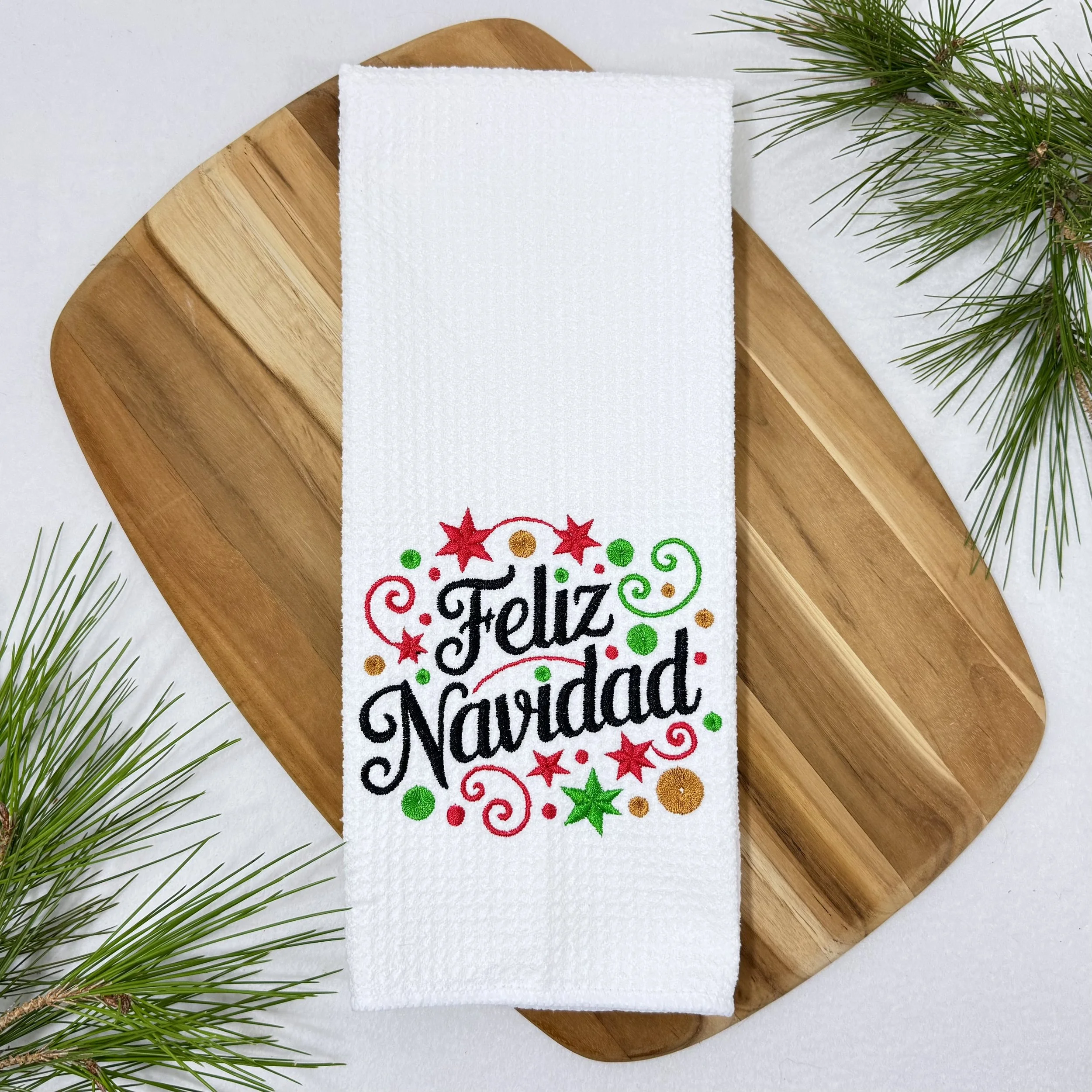 Feliz Navidad embroidered microfiber kitchen and hand towel flat lay with greenery