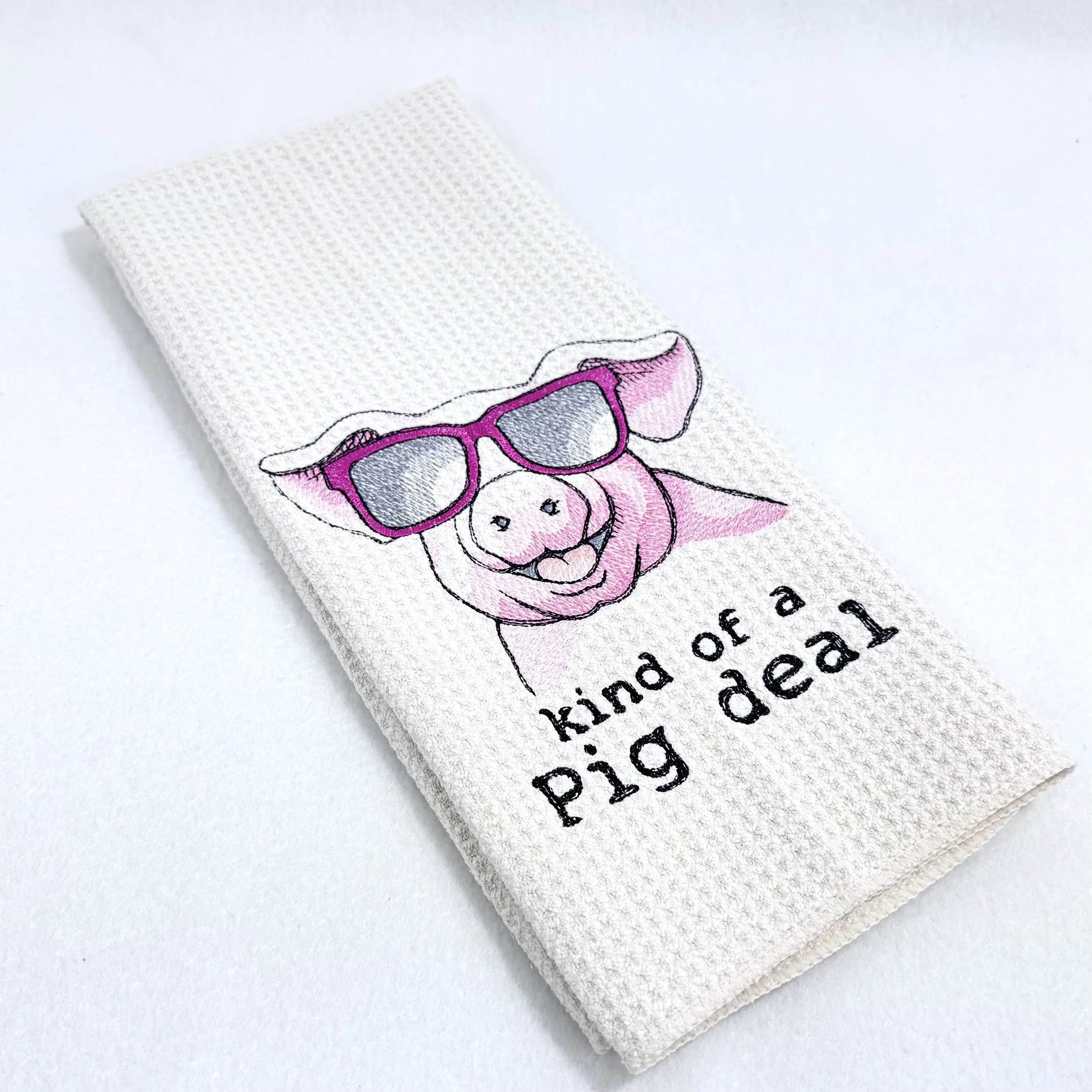 Kind of a Pig Deal embroidered microfiber kitchen and hand towel folded on white background, showing design and texture