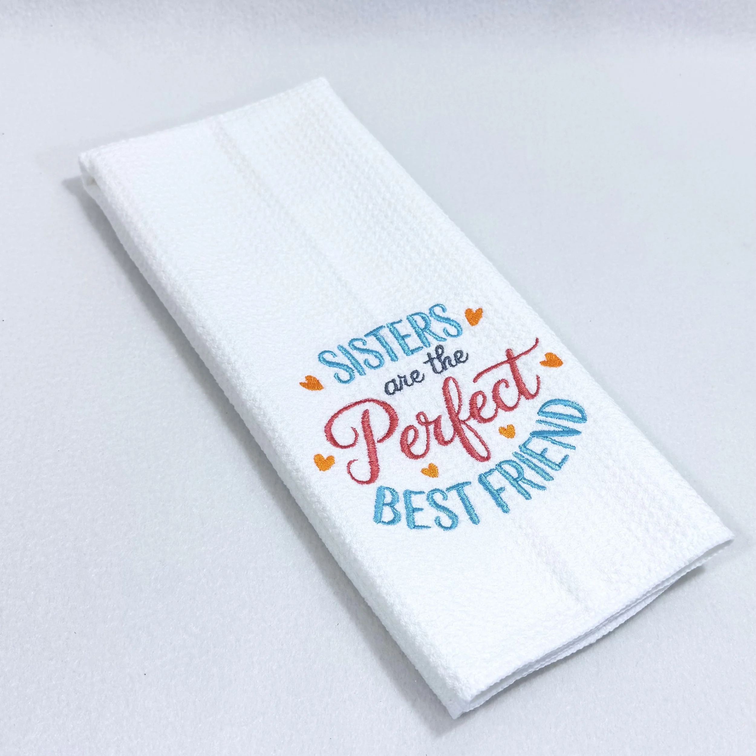 "Sisters Are The Perfect Best Friend" embroidered microfiber kitchen and hand towel folded on white background, showing colorful embroidery and towel texture