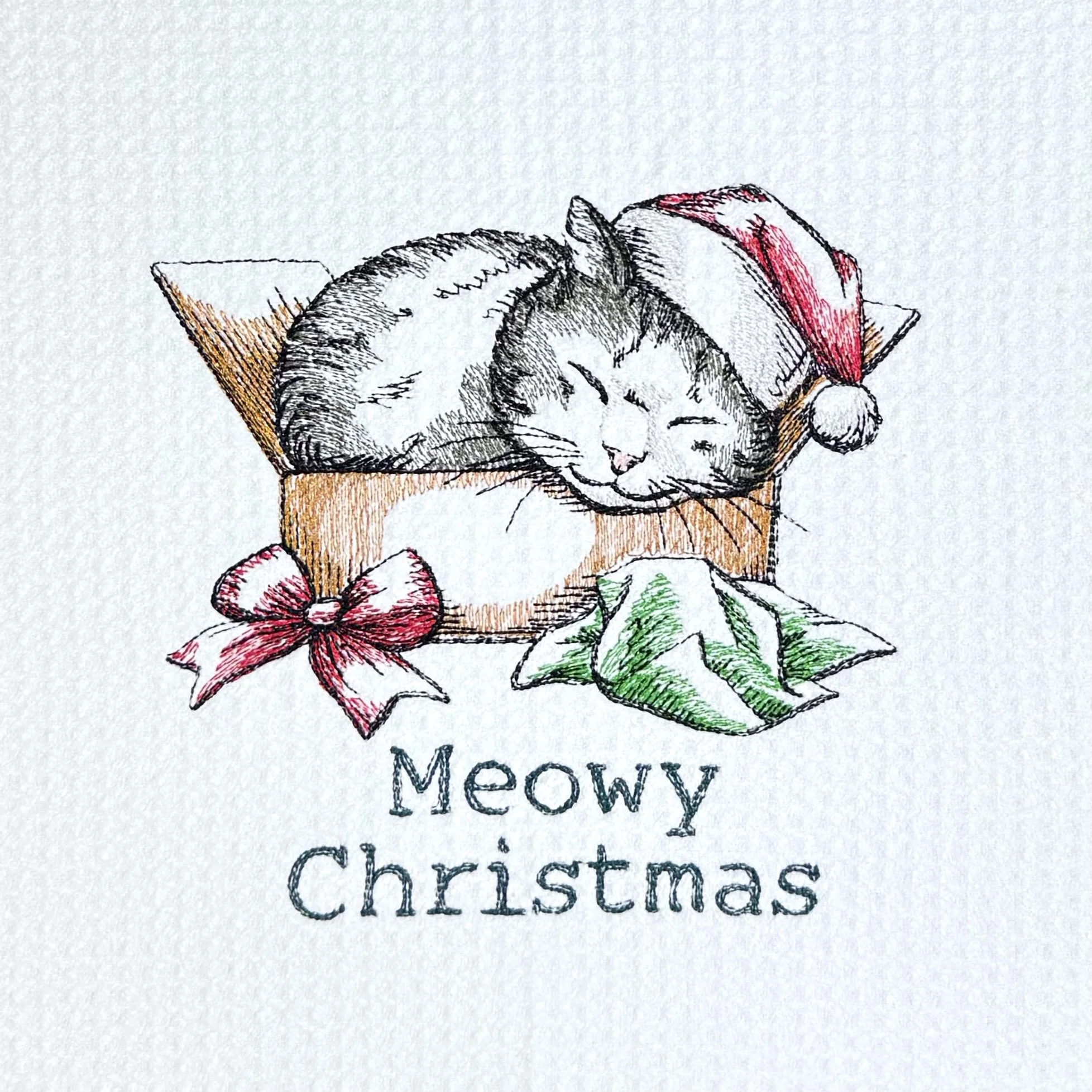 Close-up of Meowy Christmas Present embroidery on microfiber kitchen and hand Christmas towel, showing detailed stitching and towel texture