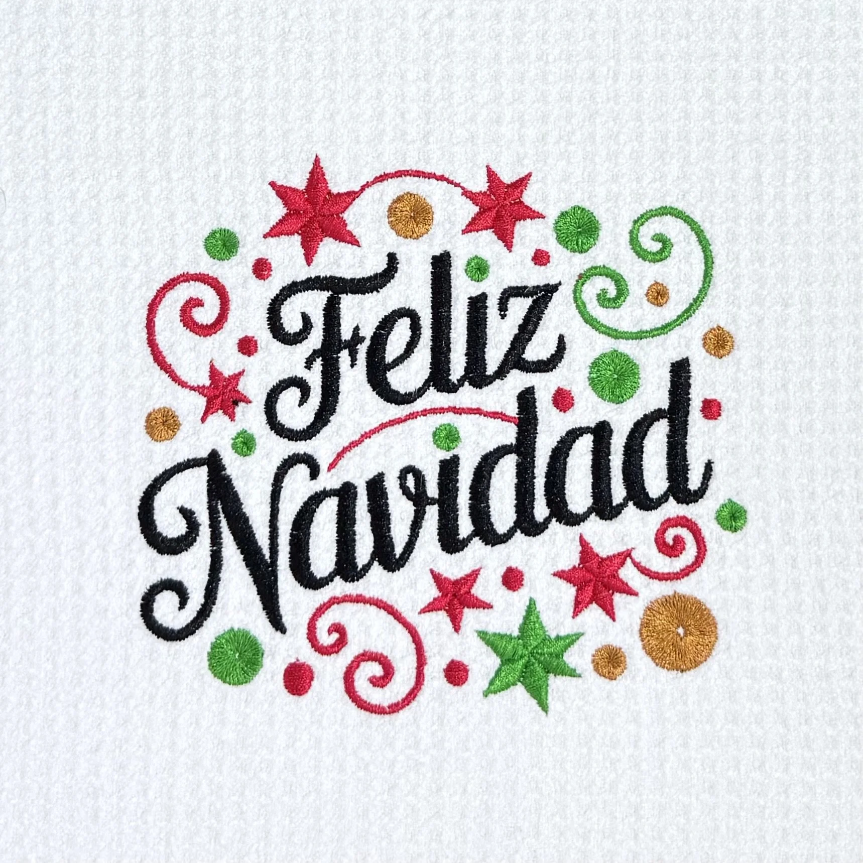 Close-up of Feliz Navidad embroidery on microfiber kitchen and hand towel, showing detailed stitching and towel texture