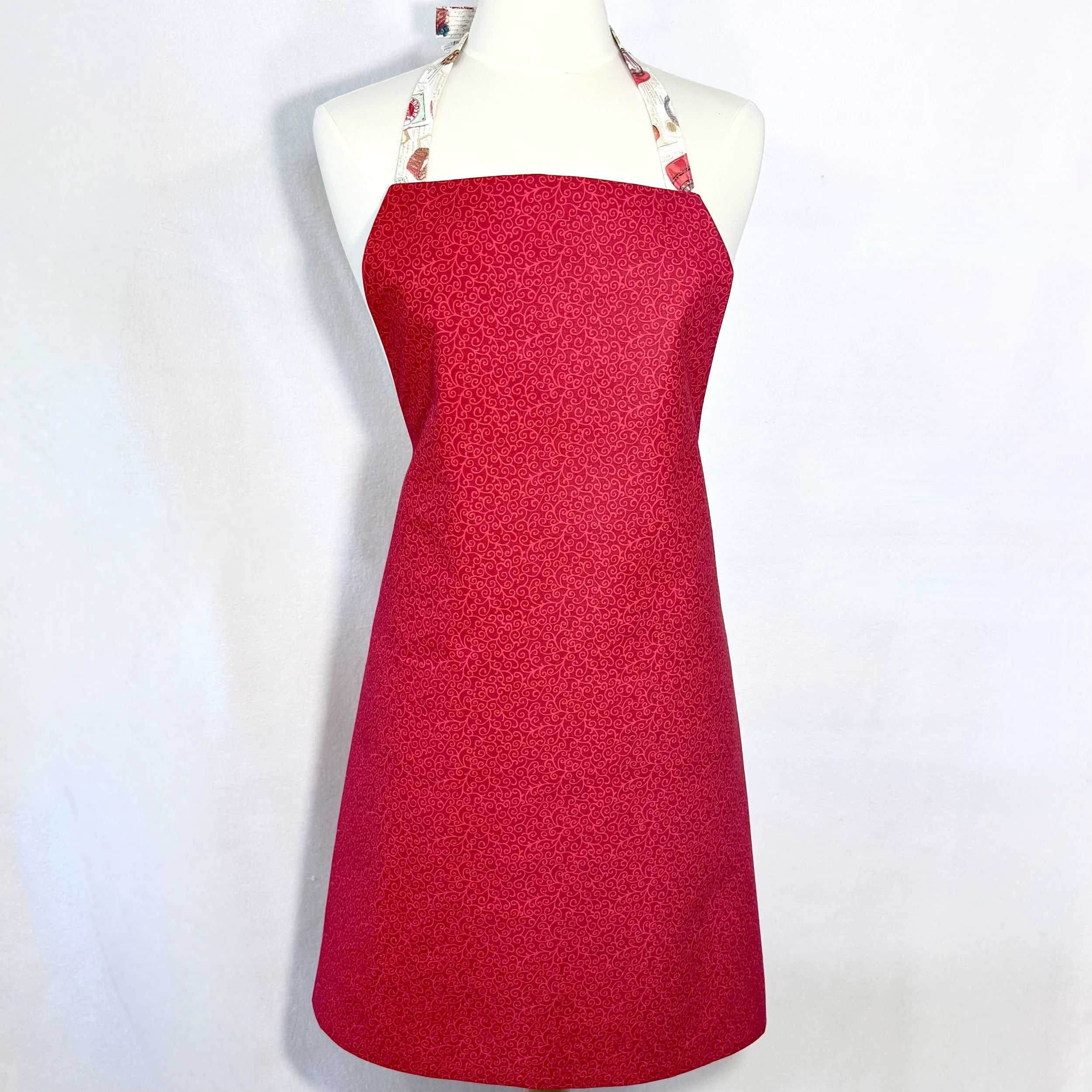 Reverse side of Just Baking Memories apron in red-on-red swirl print displayed on mannequin