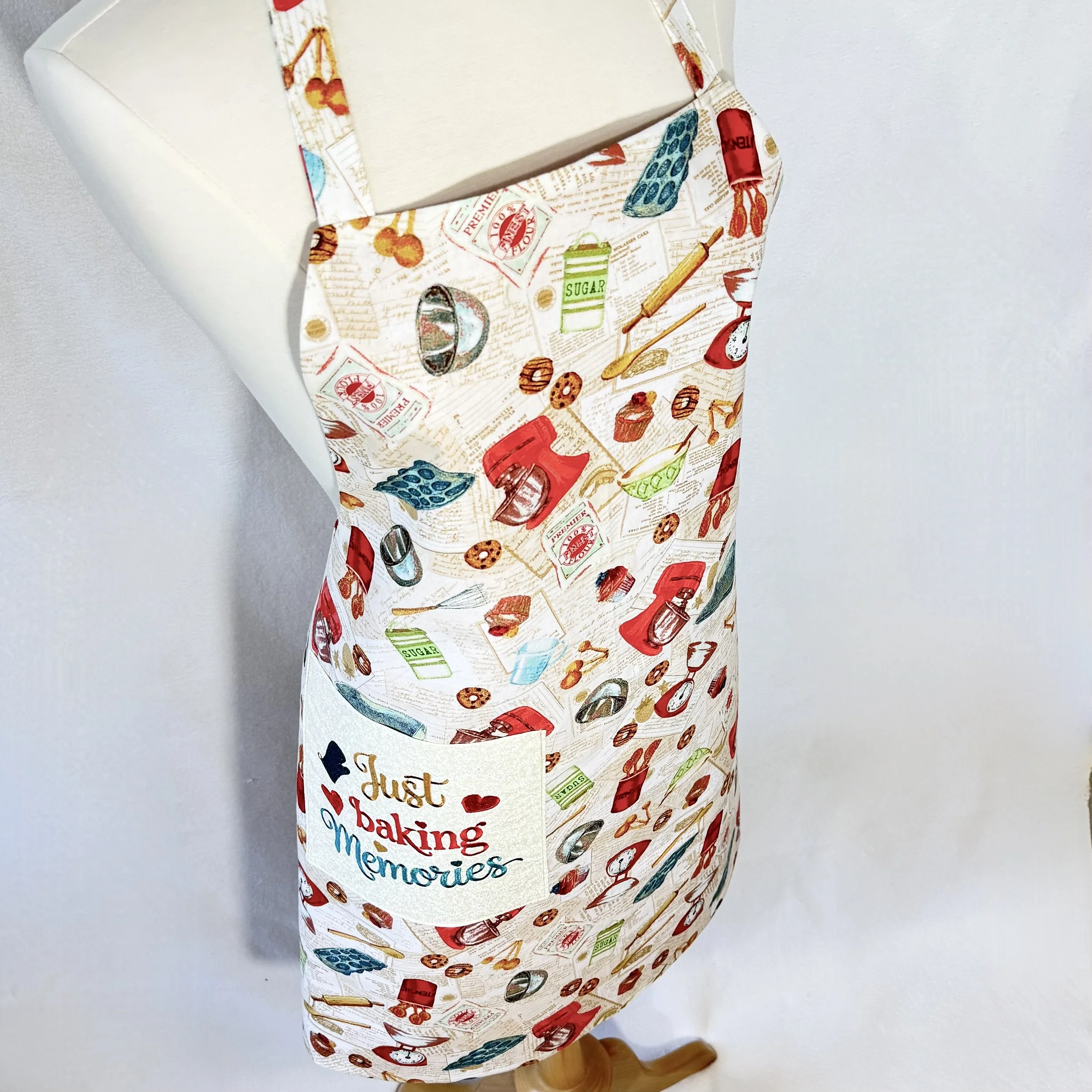 Angled view of Just Baking Memories apron on mannequin showing vintage baking print and embroidered pocket