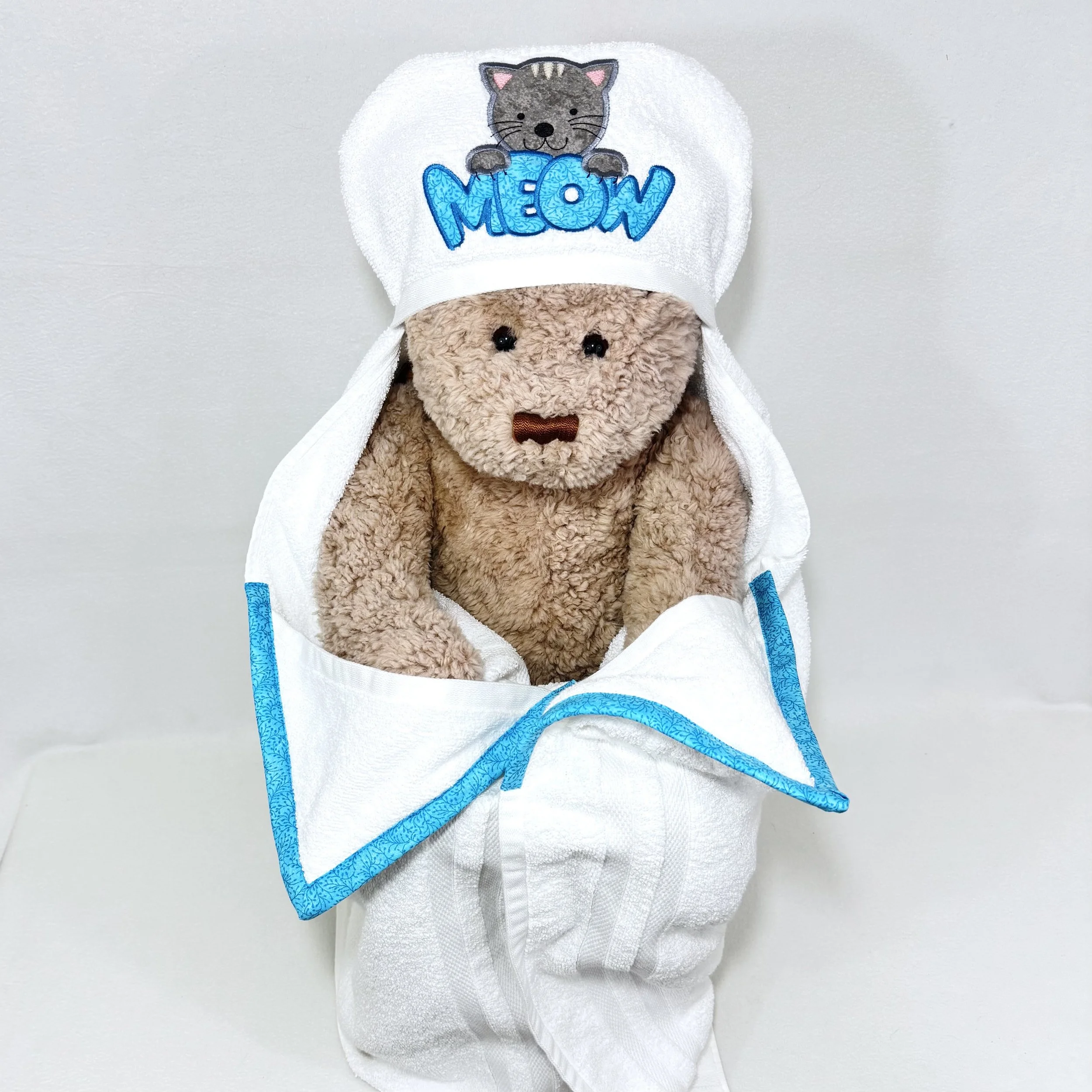 gray cat with teal meow hooded towel displayed on a teddy bear to show full size and drape when worn by a child