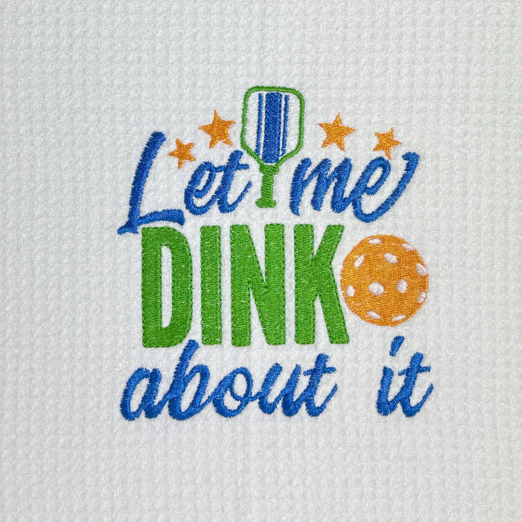 Close-up of Let Me DINK About It embroidery with pickleball paddle and ball on microfiber kitchen towel, showing detailed stitching and towel texture