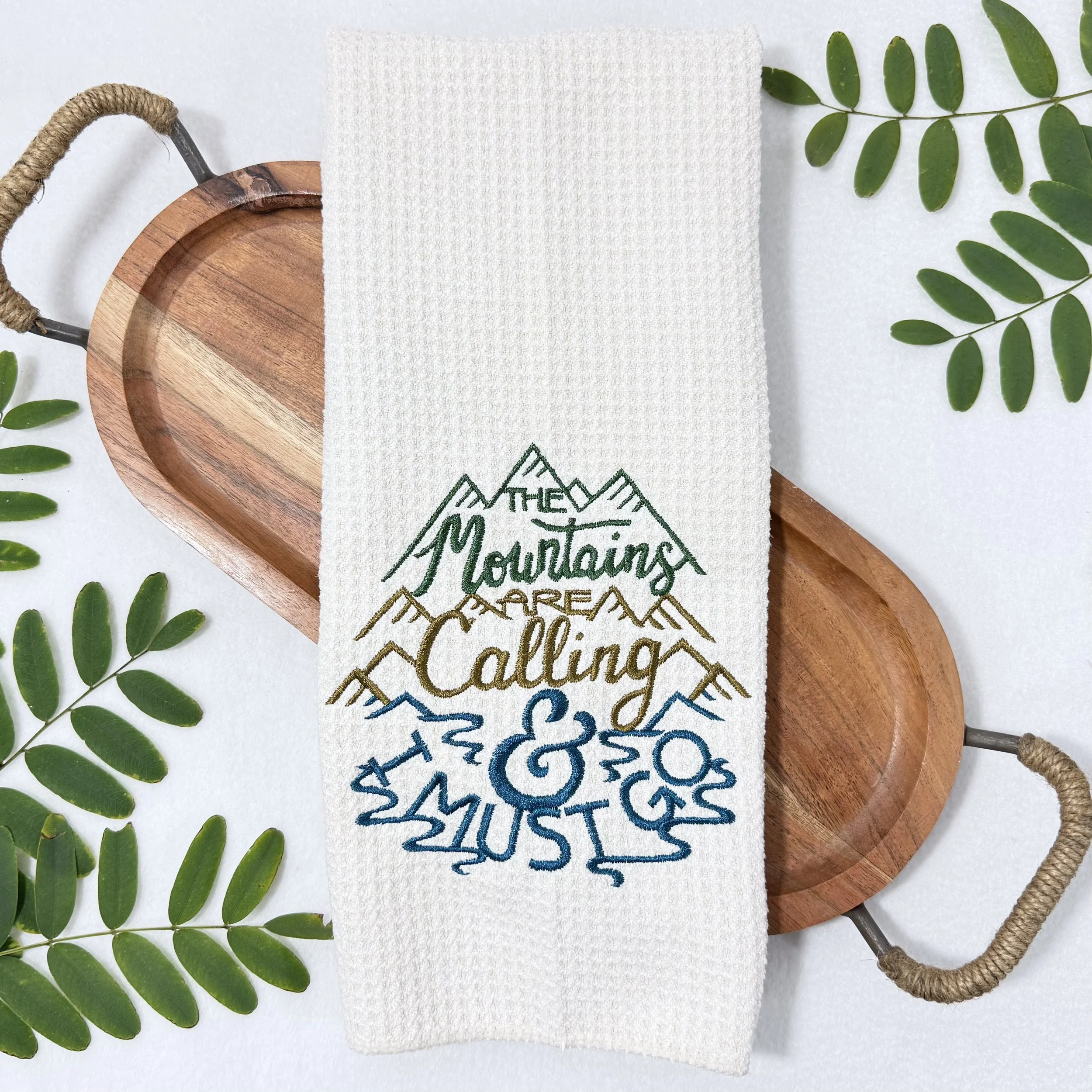 The Mountains Are Calling & I Must Go embroidered microfiber kitchen and hand towel flat lay with greenery