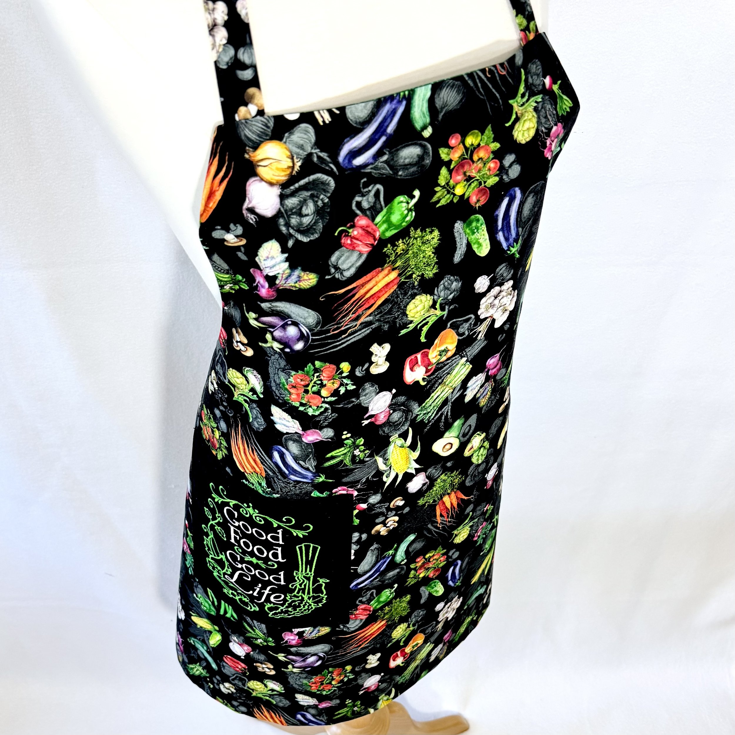 Angled view of Good Food Good Life apron on mannequin showing vegetable garden print and embroidered pocket