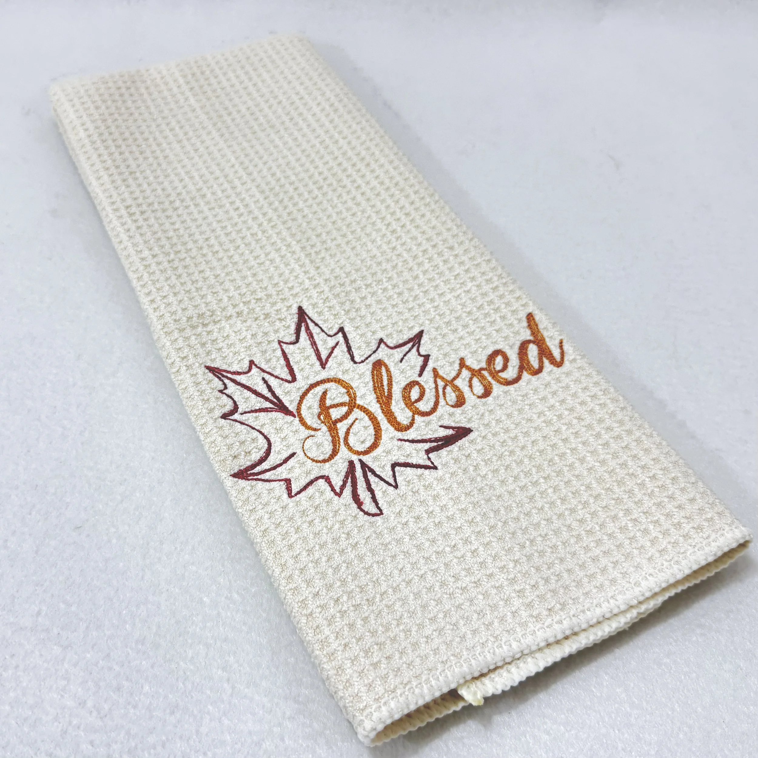 Blessed Leaf embroidered microfiber kitchen and hand towel folded on white background, showing design and texture