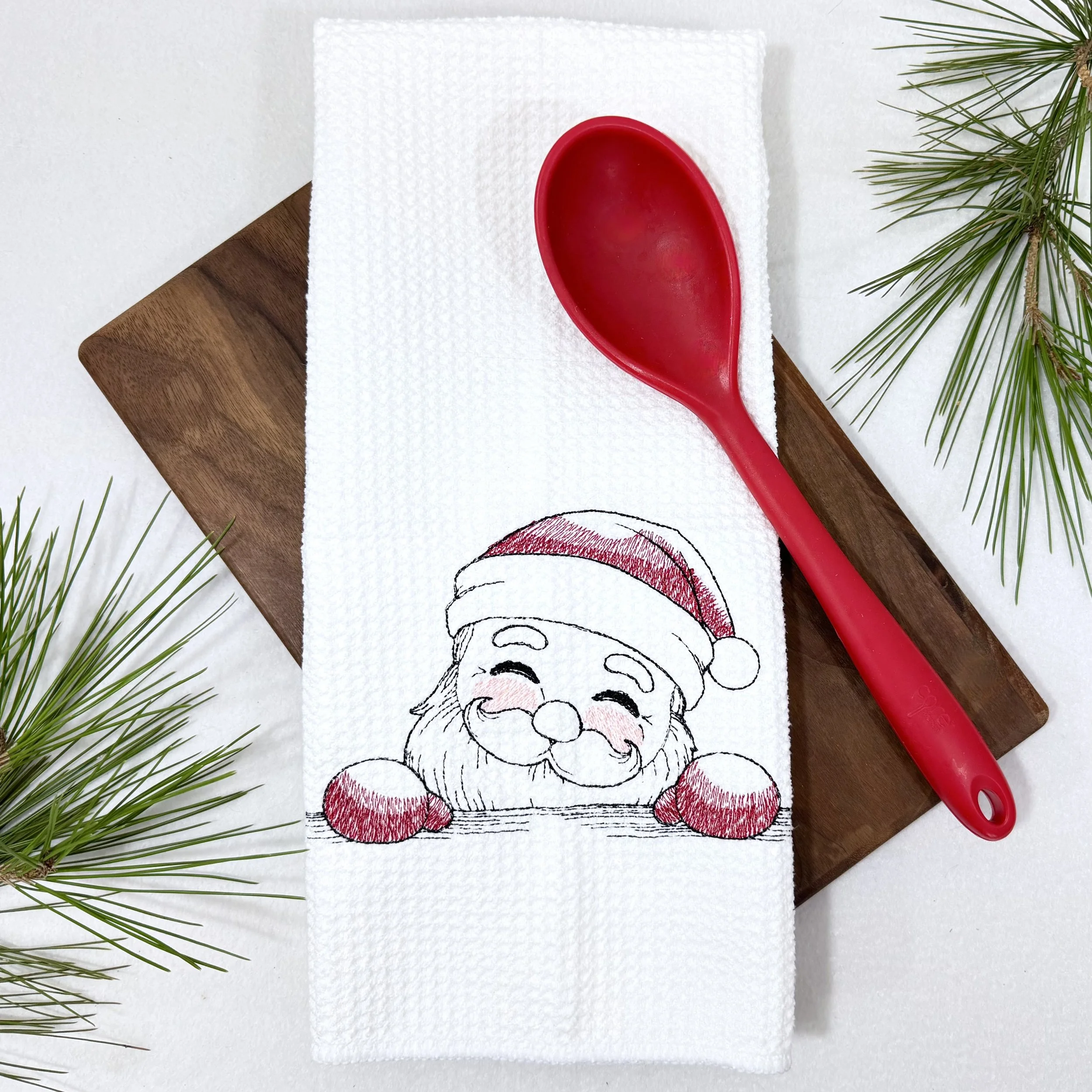 Santa Peeking embroidered microfiber kitchen and hand Christmas towel flat lay with greenery and kitchen tools