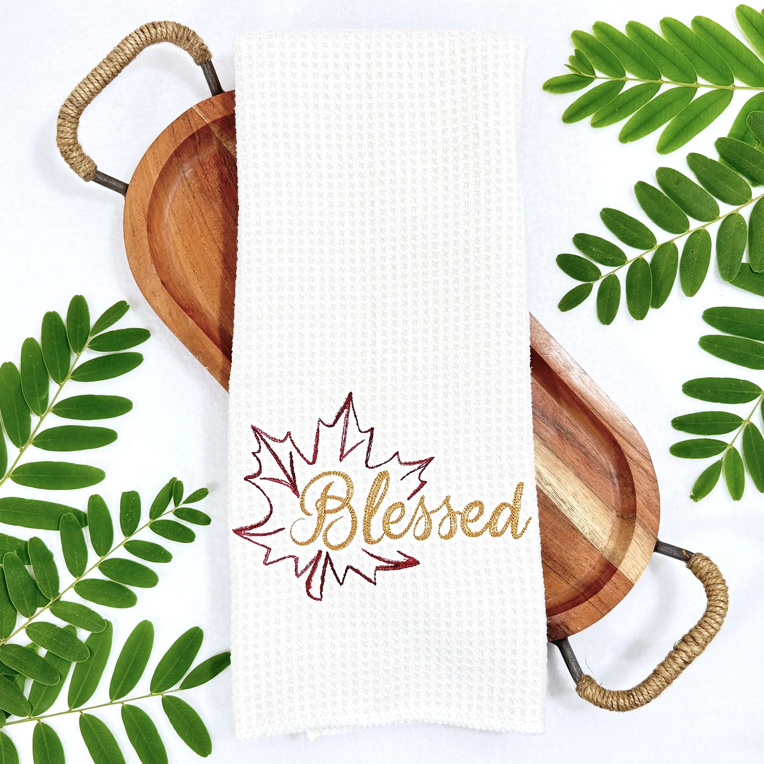 Blessed Leaf embroidered microfiber kitchen and hand towel flat lay with greenery and a wooden tray